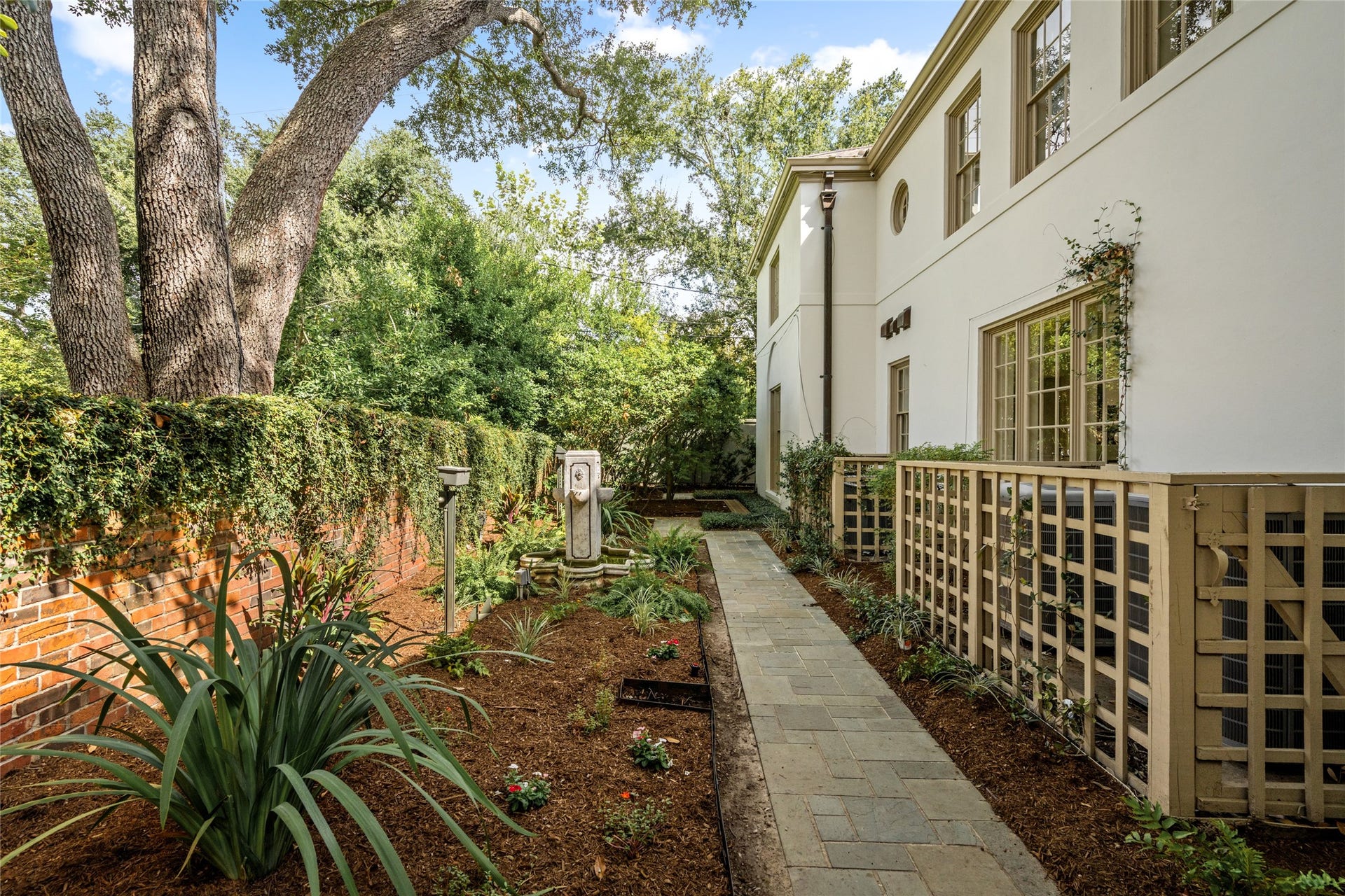 Side garden with stone walkway, decorative lattice screening, a fountain, leading to the back of the estate.