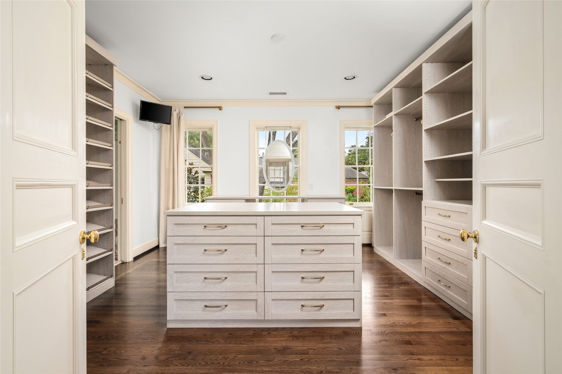 Bedroom converted into spacious dressing room with extensive built-in-storage, a central drawer island, and abundant natural light.