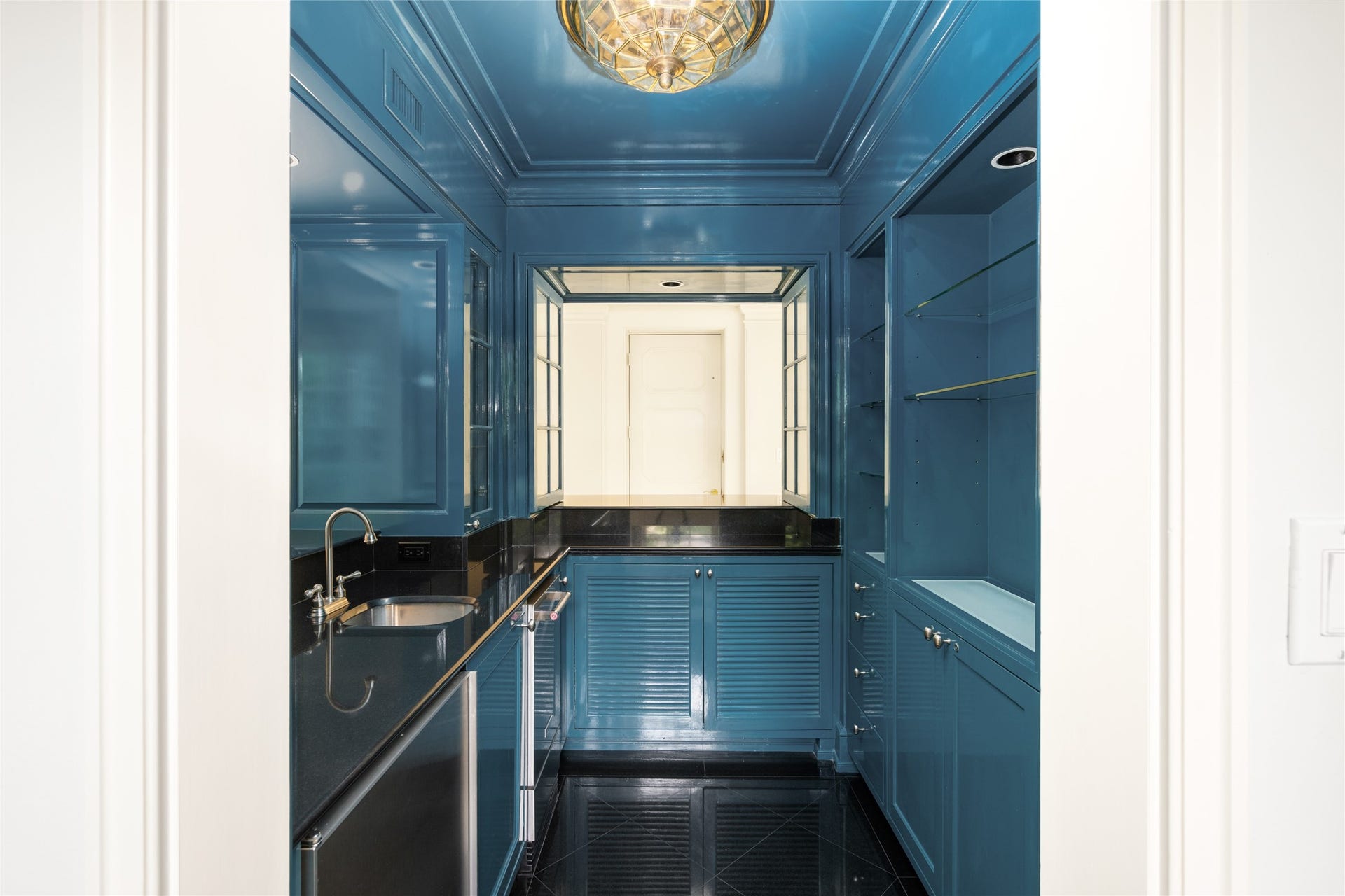 Elegant wet bar with sleek blue cabinetry, black countertops, and ample storage, perfect for entertaining.