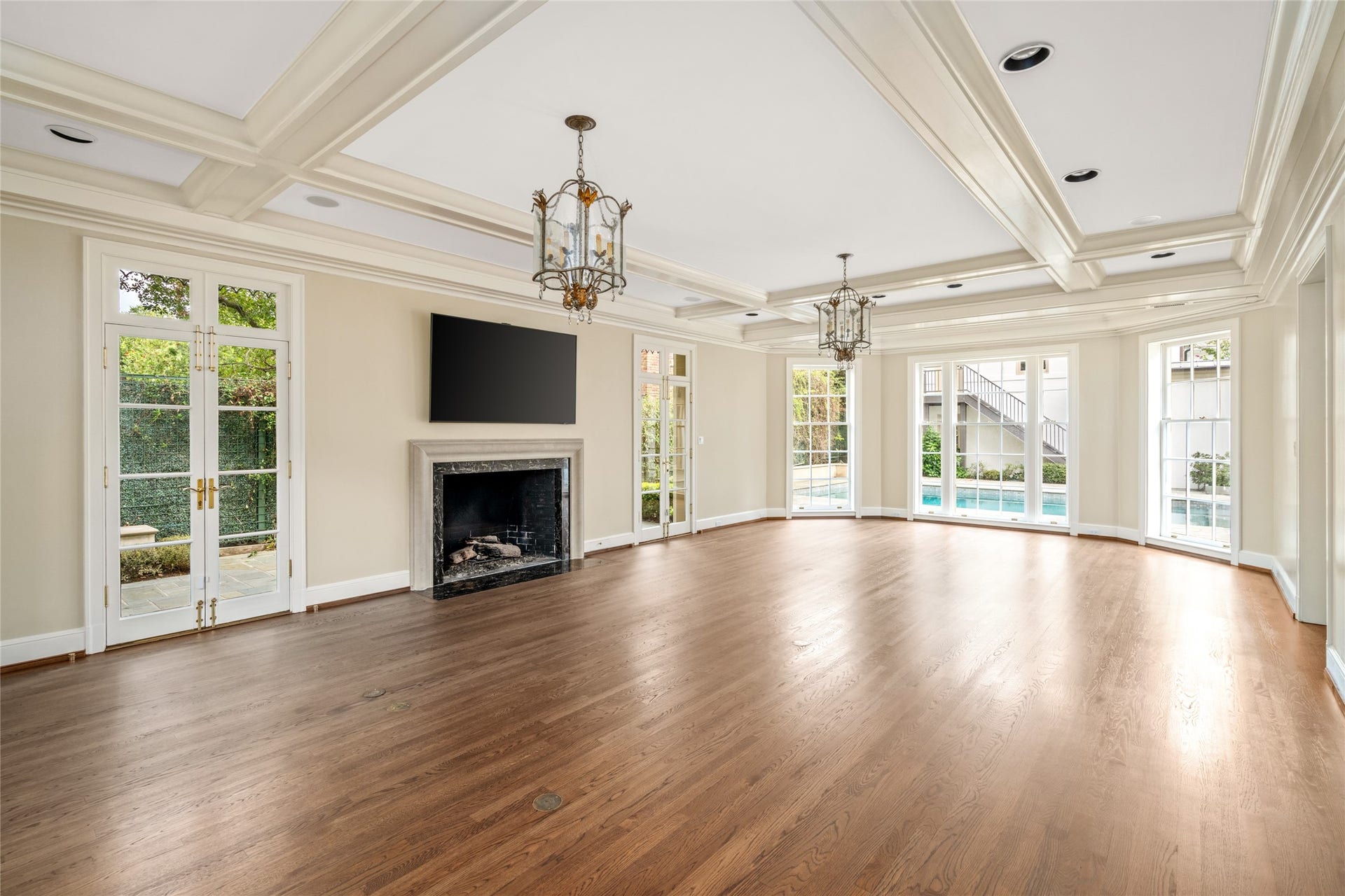 This expansive den features coffered ceiling, lantern style lighting, and a fireplace.  Rich wood floors and french doors overlooking the pool courtyard create a bright, inviting setting for everyday living and entertaining.
