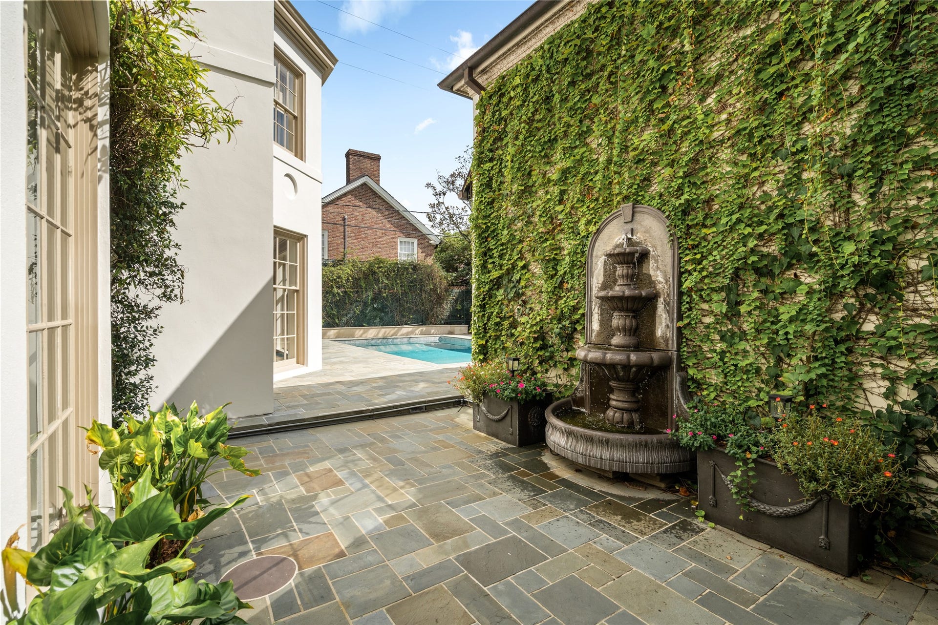 Courtyard just outside the kitchen featuring a tiered fountain, ivy covered wall, and access to the pool.