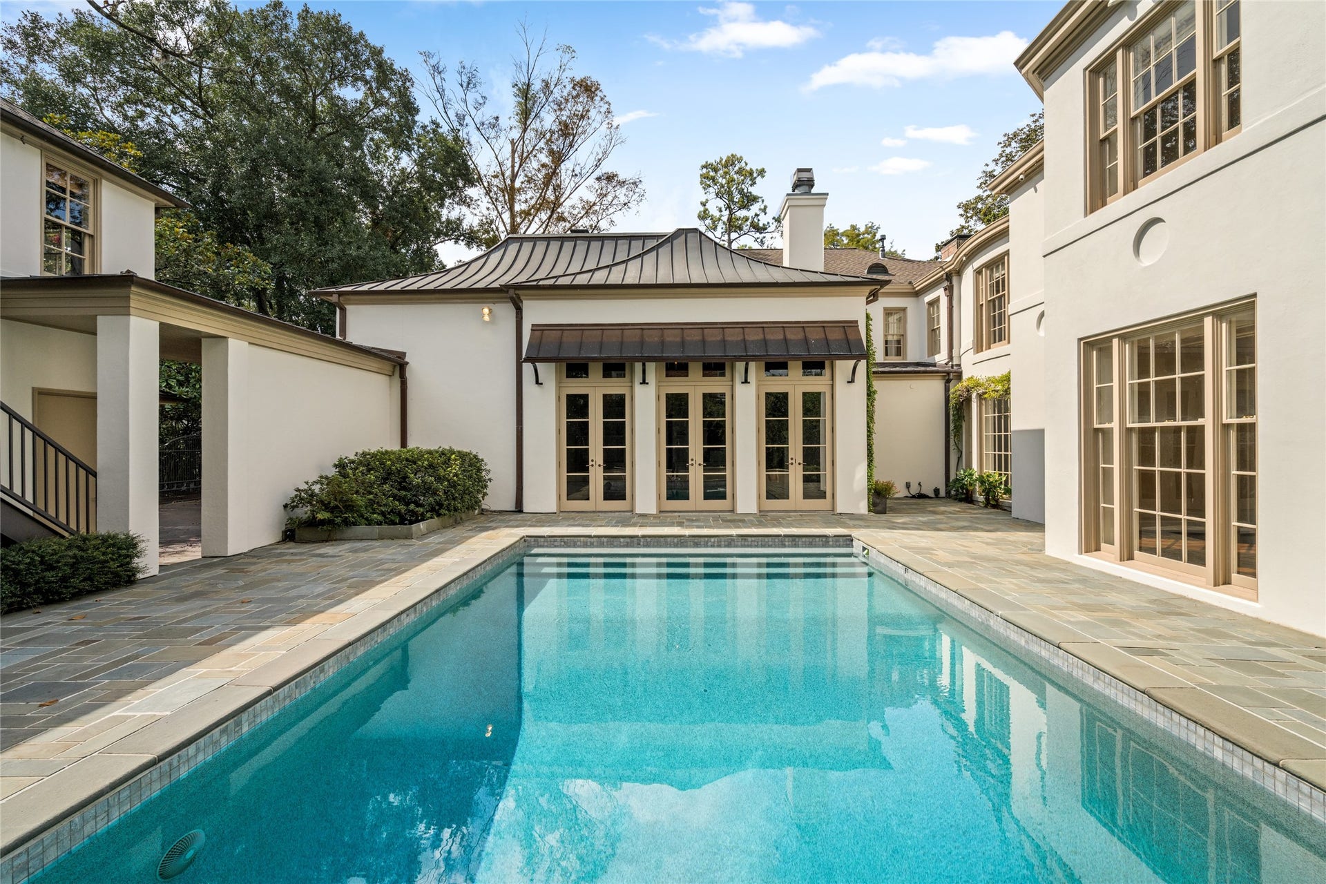 A sparkling pool anchors this elegant courtyard, framed by stone paving, tall windows, and French doors.  The inviting setting offers a beautiful backdrop for outdoor entertaining and quiet afternoons by the water.