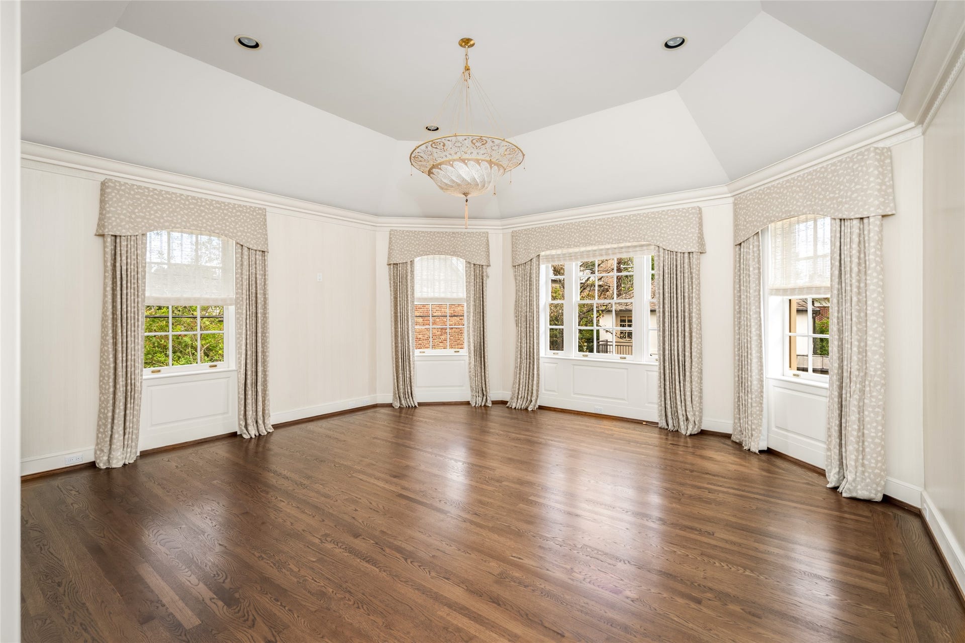 Spacious primary bedroom overlooking the pool, featuring a tray ceiling and abundant lighting.
