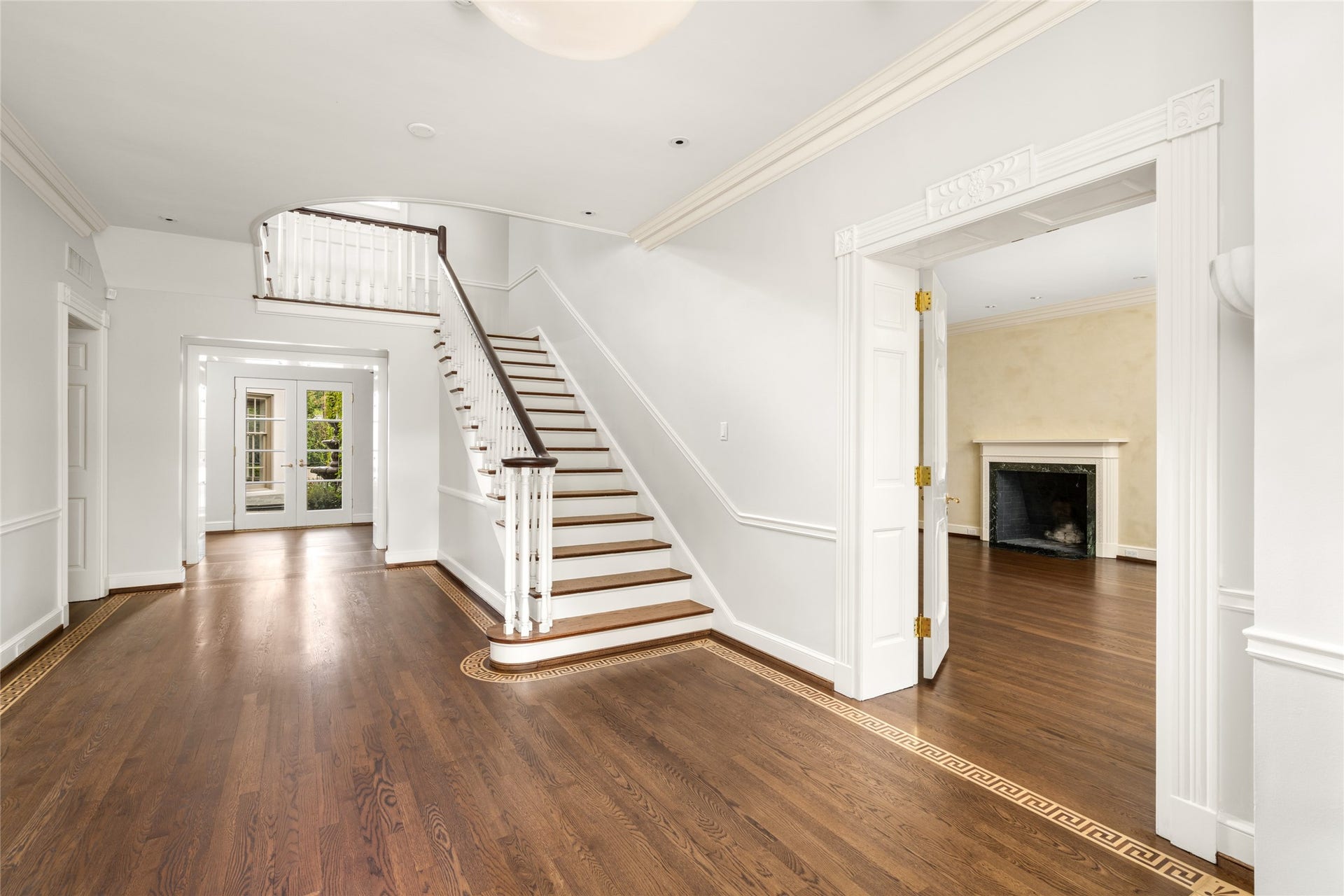 A gracious entrance hall showcases a sweeping staircase, rich newly refurbished floors with a decorative inlaid border, and a beautifully detailed mill work.  Wide doorways connect the foyer to adjoining living spaces, creating an elegant welcome and an inviting flow for entertaining.