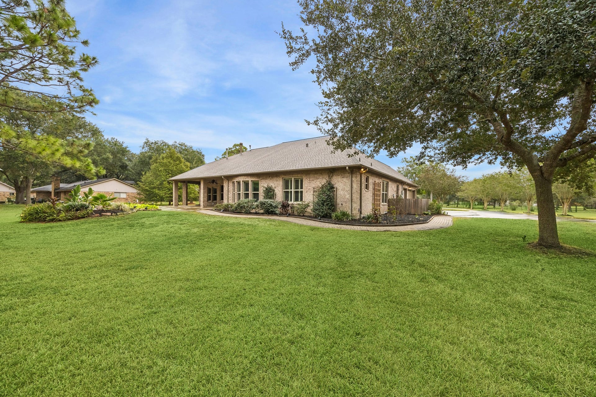 Charming brick home with a spacious, well-manicured lawn and mature trees, offering a serene and inviting outdoor space.