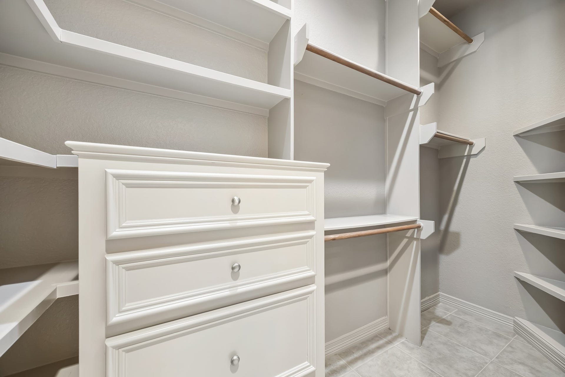 Spacious walk-in closet featuring built-in shelving, ample hanging space, and elegant cabinetry for organized storage.