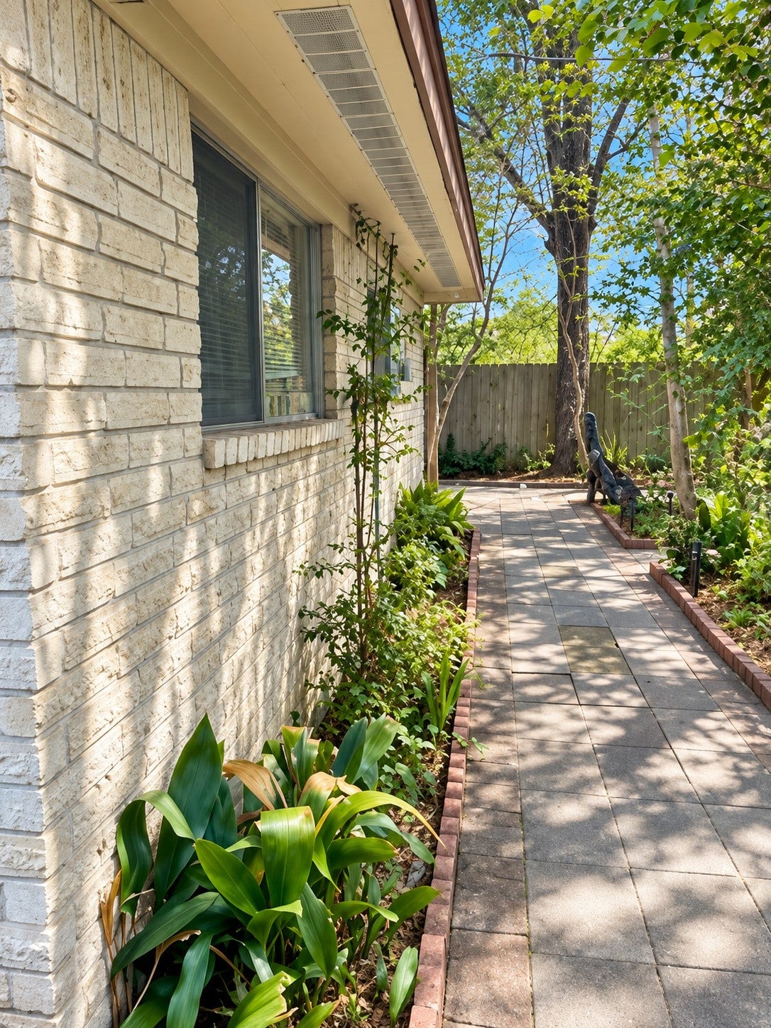 17555 Methil Drive, Spring, TX 77379 Charming outdoor walkway featuring attractive stone pavers, lush landscaping, mature trees, and beautifully maintained garden beds. The surrounding greenery provides natural shade and creates a peaceful, private setting to enjoy the outdoors.