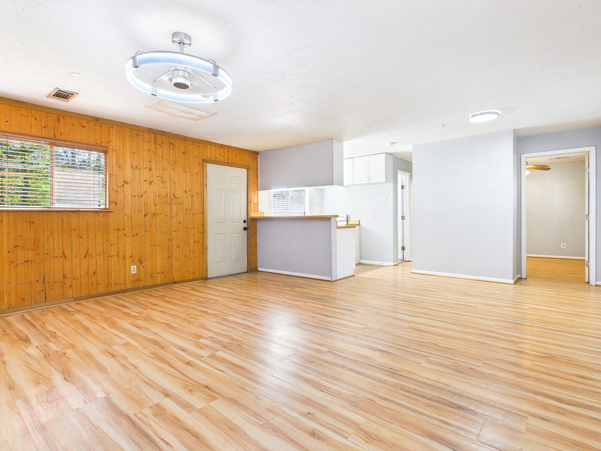 22054 Spears Road, Porter, TX 77365 Spacious open-concept living area with warm wood paneling, sleek wood-look floors, and modern lighting, seamlessly connected to a cozy kitchen.