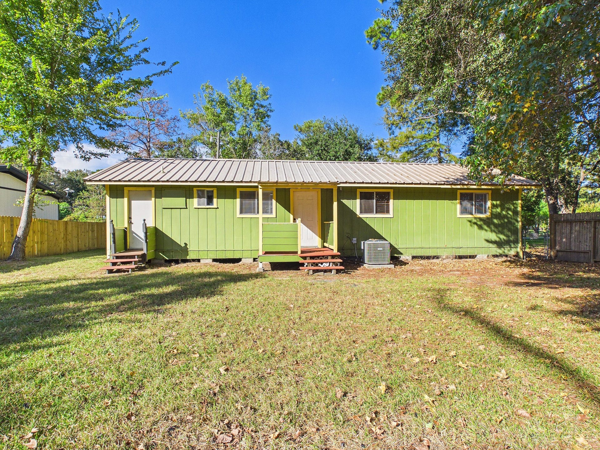 22054 Spears Road, Porter, TX 77365 Charming home with a metal roof, set on a spacious grassy lot, surrounded by mature trees for added privacy.