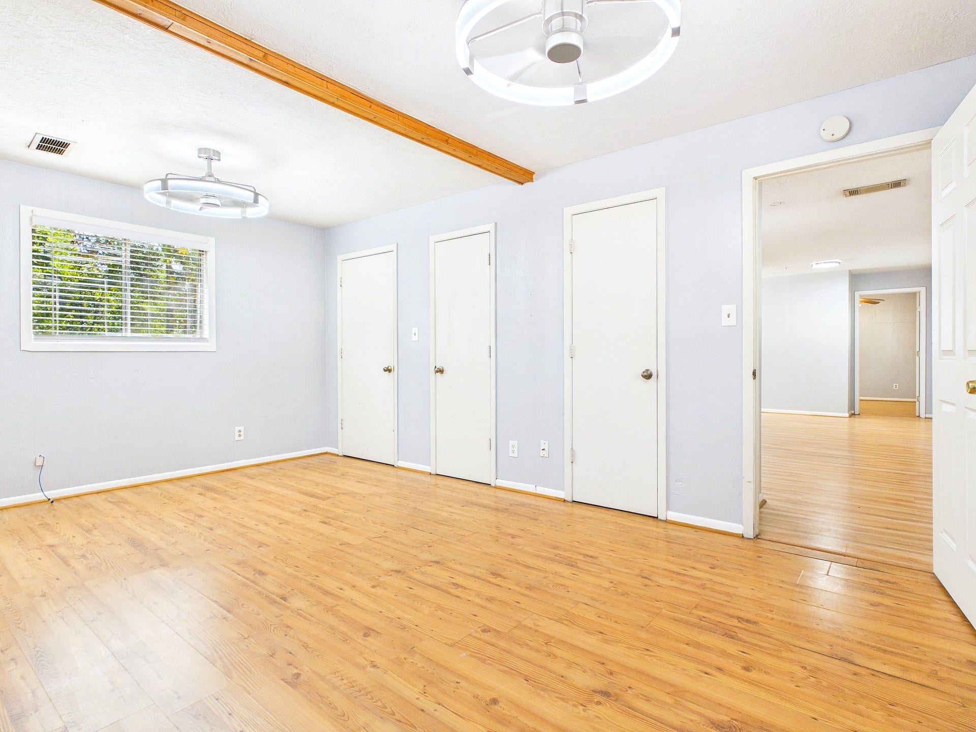 22054 Spears Road, Porter, TX 77365 Spacious room with warm wood-look flooring, modern lighting, and ample natural light from a large window, offering versatile storage with multiple doors.