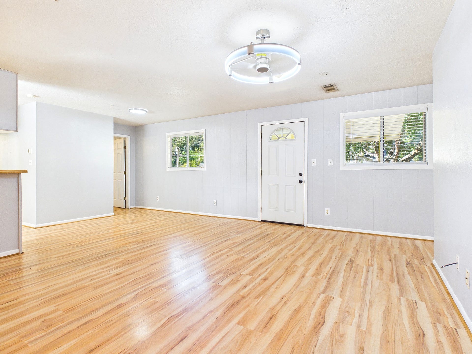 22054 Spears Road, Porter, TX 77365 Bright and spacious living area featuring sleek wood-look floors, modern lighting, and ample natural light from large windows, perfect for comfortable living and entertaining.
