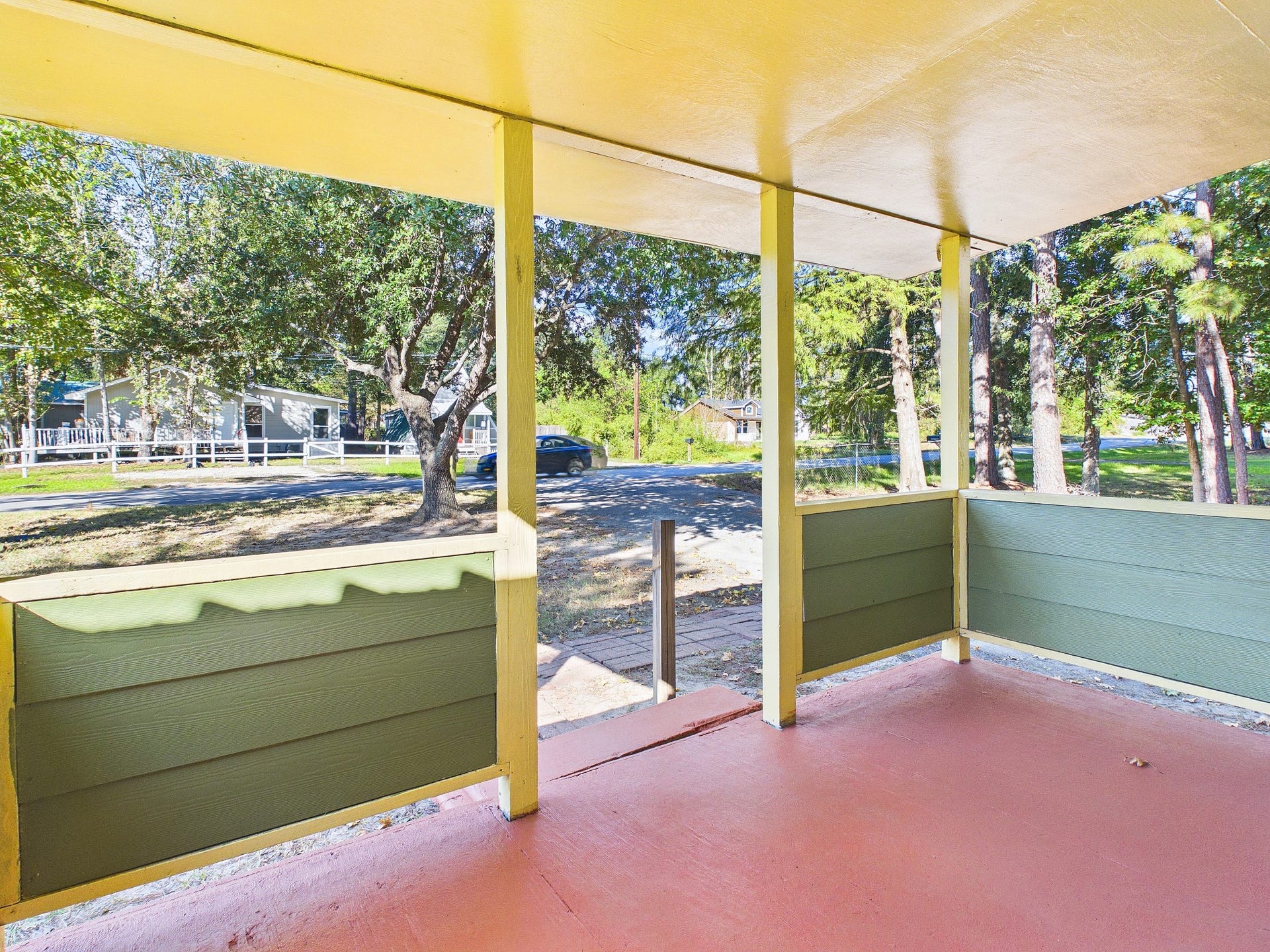 22054 Spears Road, Porter, TX 77365 Charming front porch with colorful details offers a serene view of lush trees and a quiet neighborhood street.