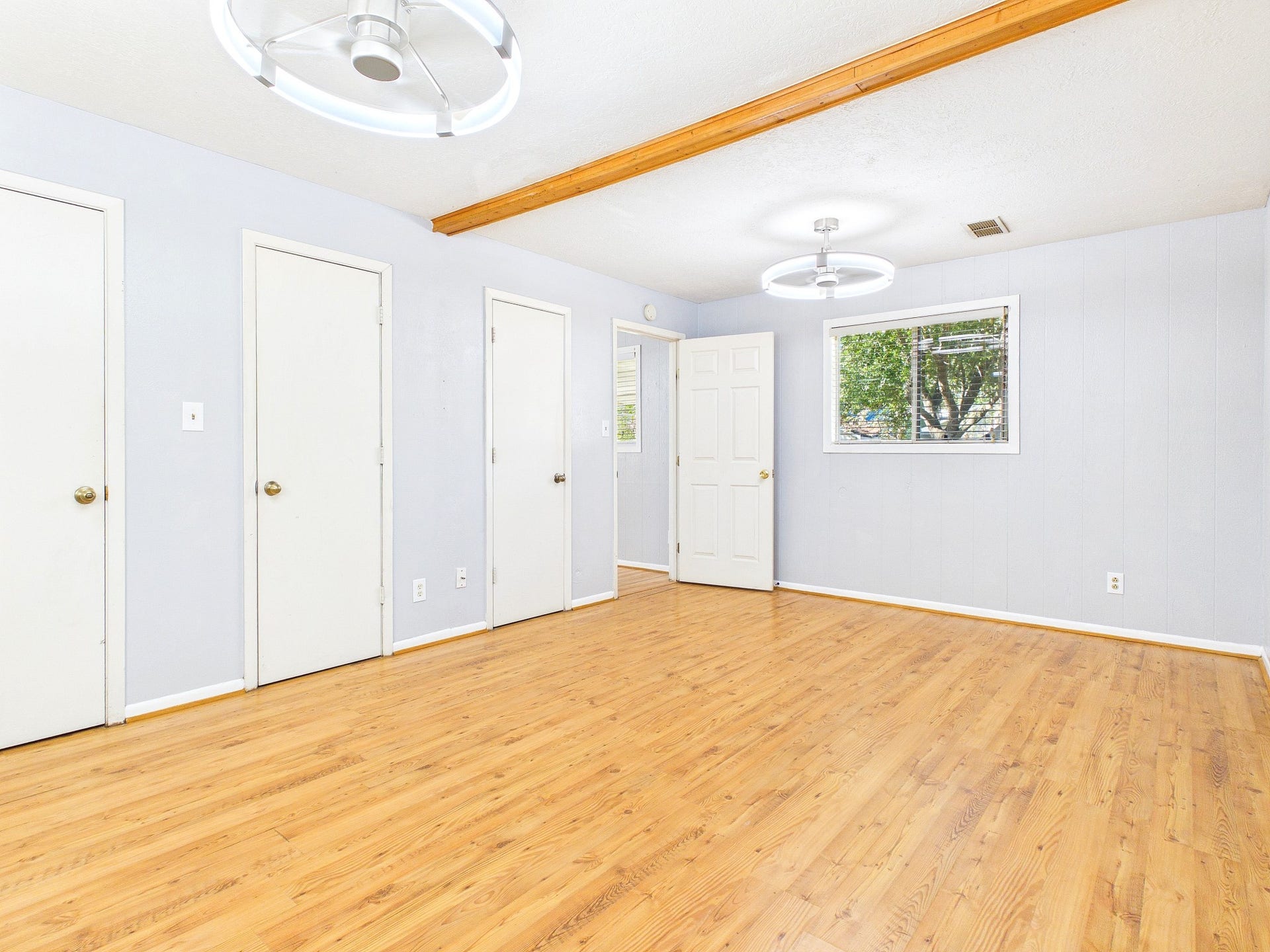 22054 Spears Road, Porter, TX 77365 Spacious and bright room featuring sleek flooring, modern light fixtures, and ample storage with multiple doors, creating a versatile living space.