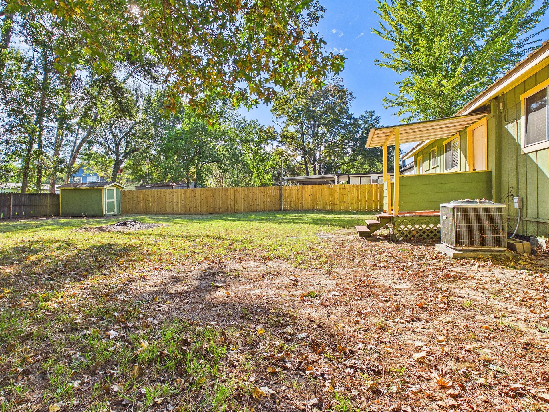 22054 Spears Road, Porter, TX 77365 Spacious backyard with mature trees, a storage shed, and a charming covered porch, perfect for outdoor relaxation and activities.