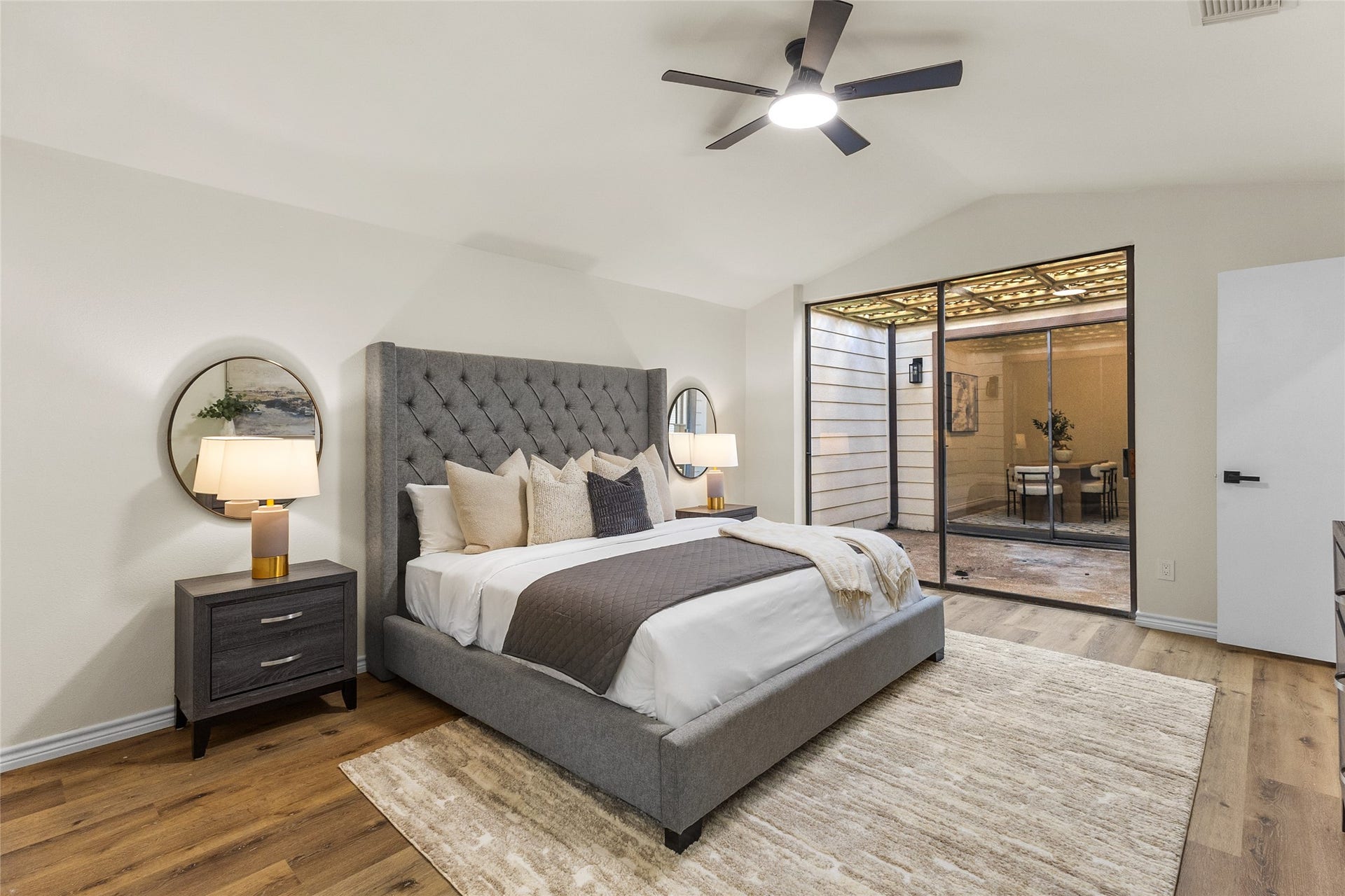 Located on the first floor, your spacious primary bedroom features warm wood-look flooring, a modern ceiling fan, and soft neutral finishes.