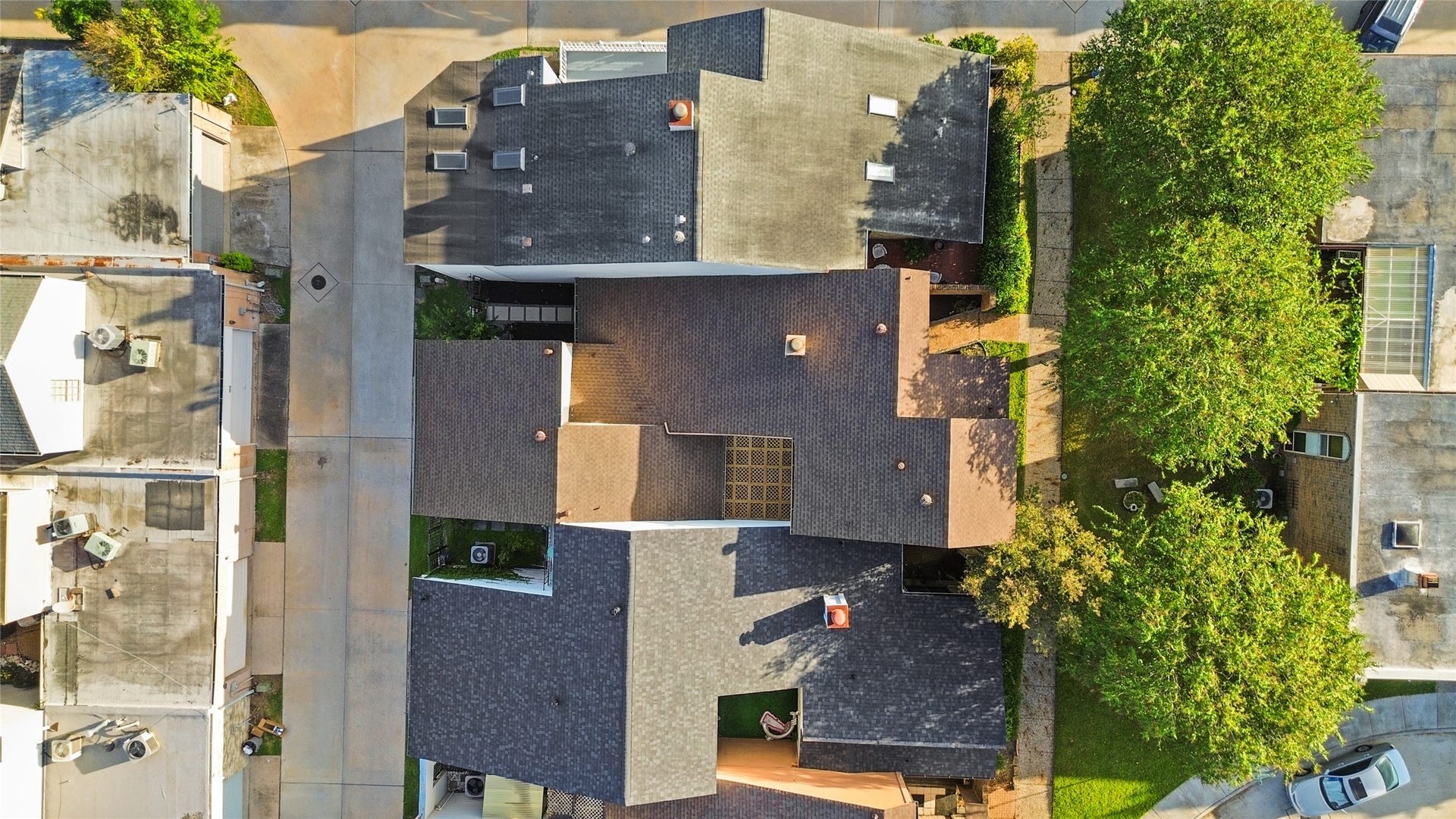 Bird's-eye view highlights the residential layout, distinctive rooflines, mature landscaping, and surrounding walkways and access roads.