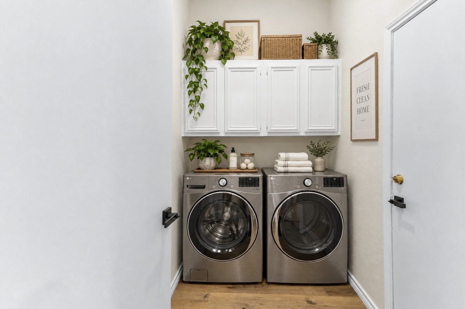 Loctaed off the kitchen, your convenient laundry room features white overhead storage cabinets, washer and dryer hookups, crisp neutral walls, and warm wood-look flooring for a clean and functional space. Garage access to the right. This space has been virtually staged using AI.