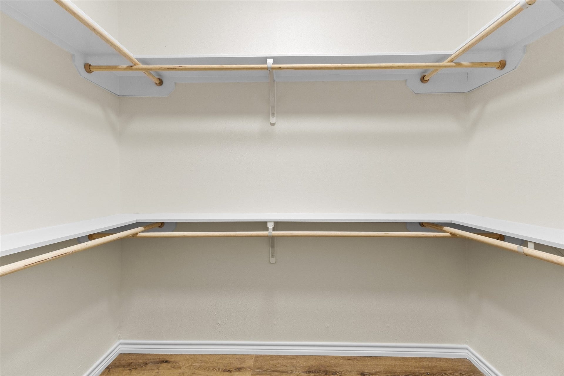The primary bedrooms generously sized walk-in closet features wraparound shelving, multiple hanging rods, plus built-in shelving off to the side for additional storage and organization.