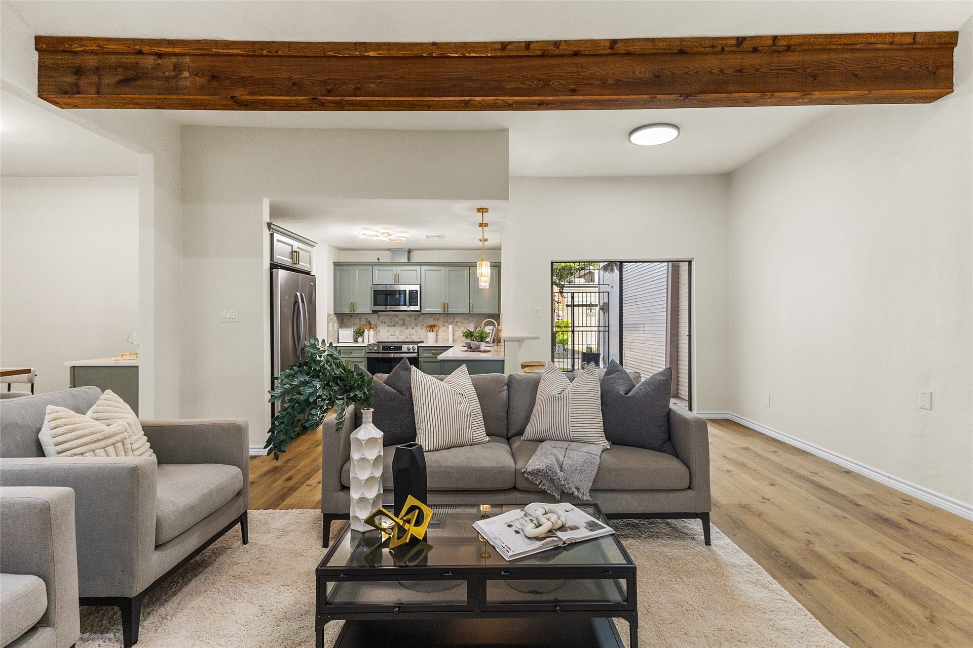Beautiful updated, your living area showcases a striking exposed wood ceiling beam that adds warmth and architectural character, complemented by rich wood-look flooring, contemporary finishes, and a spacious, open-concept layout. The inviting space flows seamlessly into the kitchen and dining areas, creating a comfortable setting for everyday relaxation, gatherings, and entertaining guests.