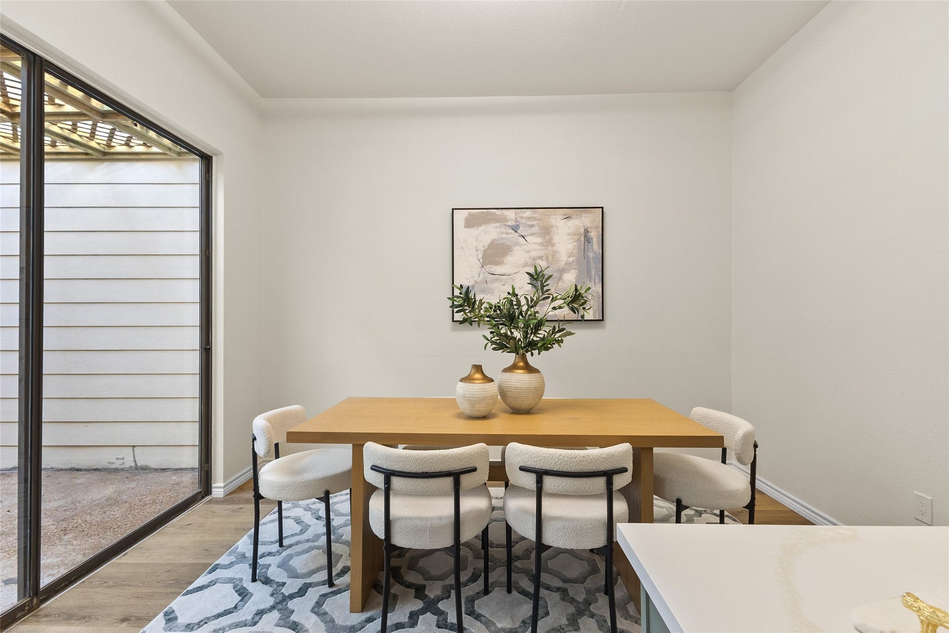 Your inviting dining area features warm wood-look flooring, neutral-toned walls, and a spacious layout ideal for everyday meals or entertaining guests. A built-in buffet with sage green cabinetry, gold hardware, and a quartz countertop adds both style and storage.