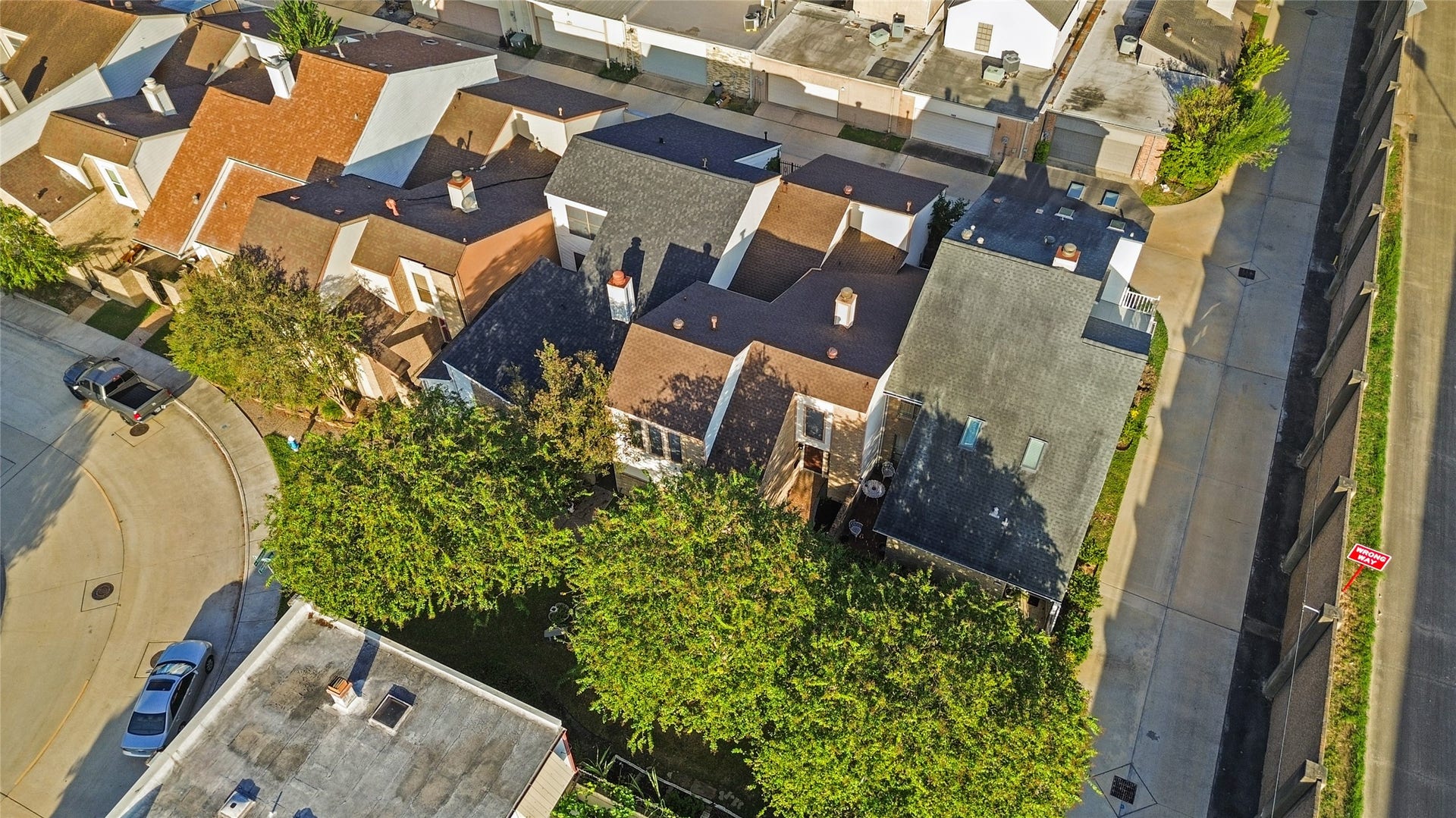 Aerial view highlights the surrounding residential community, mature tree canopy, neighboring homes, and convenient rear alley access.