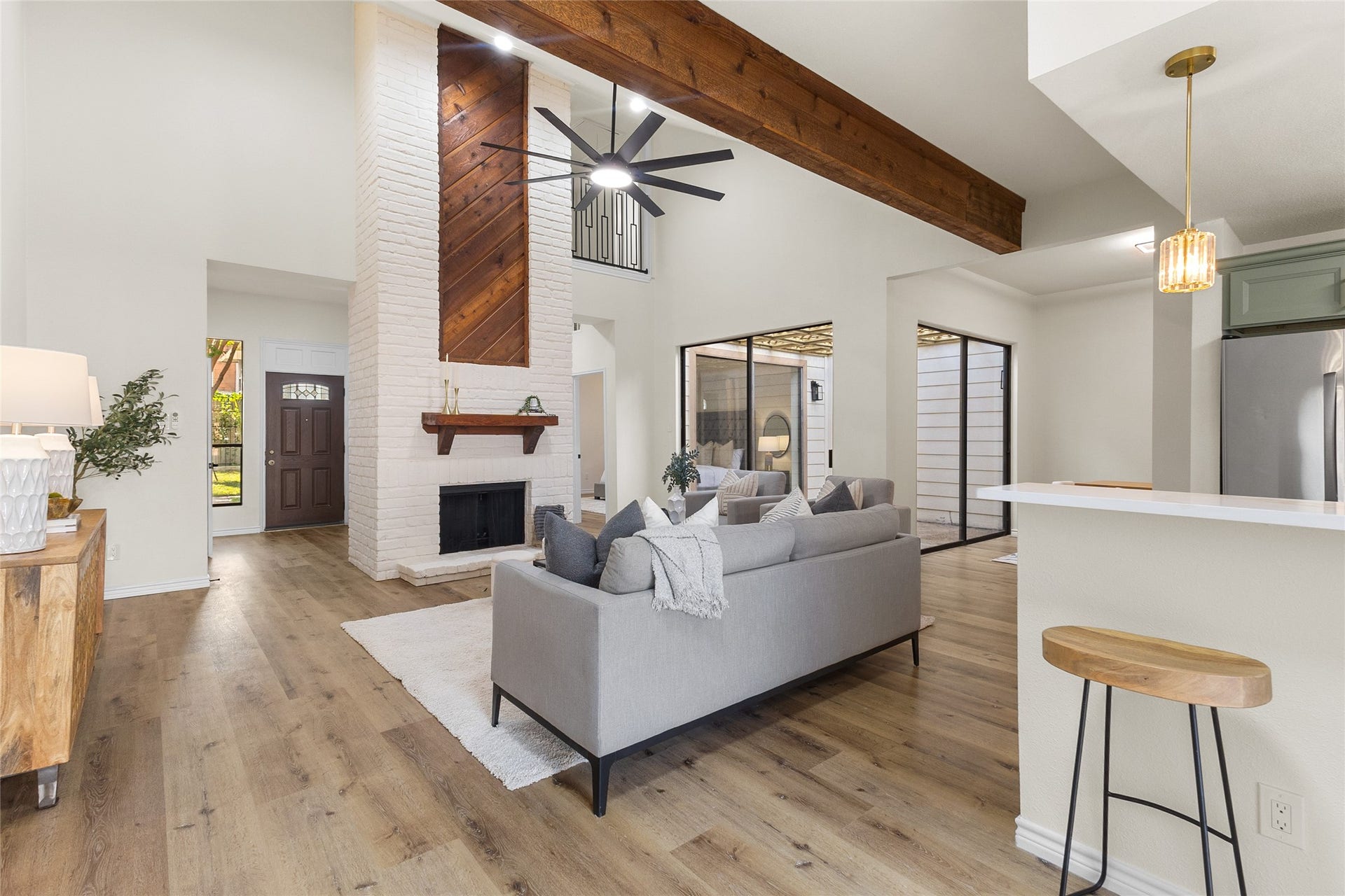 Enter your open-concept living space that combines rustic charm with modern finishes, featuring a brick fireplace, rich wood accents, high ceilings, and seamless access to the kitchen and dining areas. Floor-to-ceiling glass overlooks a private interior atrium that brings natural light into the center of the home.