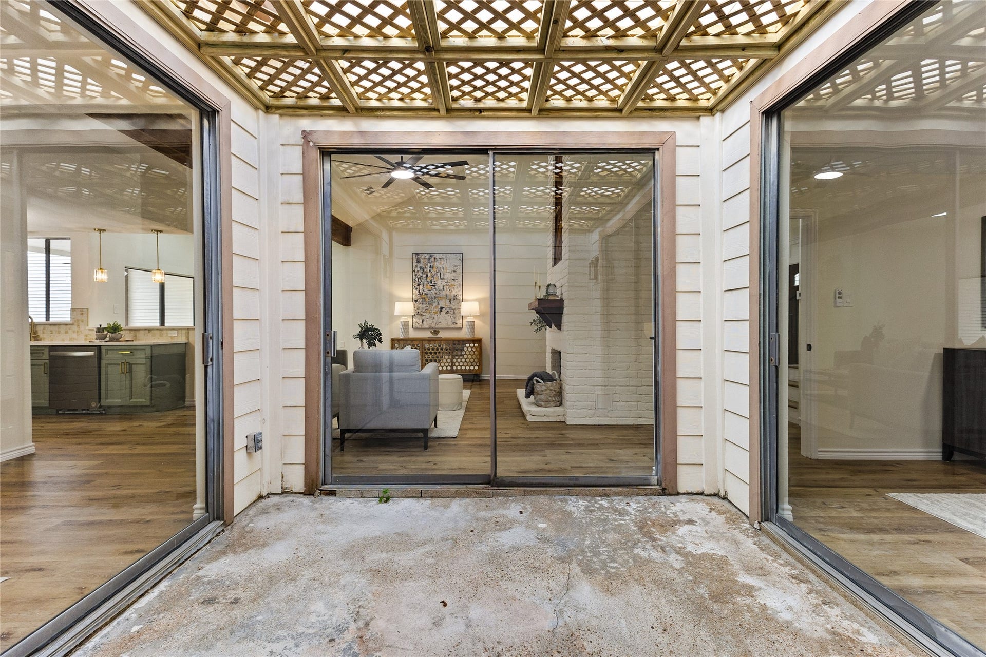 Your atrium features a decorative wooden lattice pergola, concrete patio, and surrounding sliding glass doors that connect the indoor living spaces while allowing natural light to flow throughout.