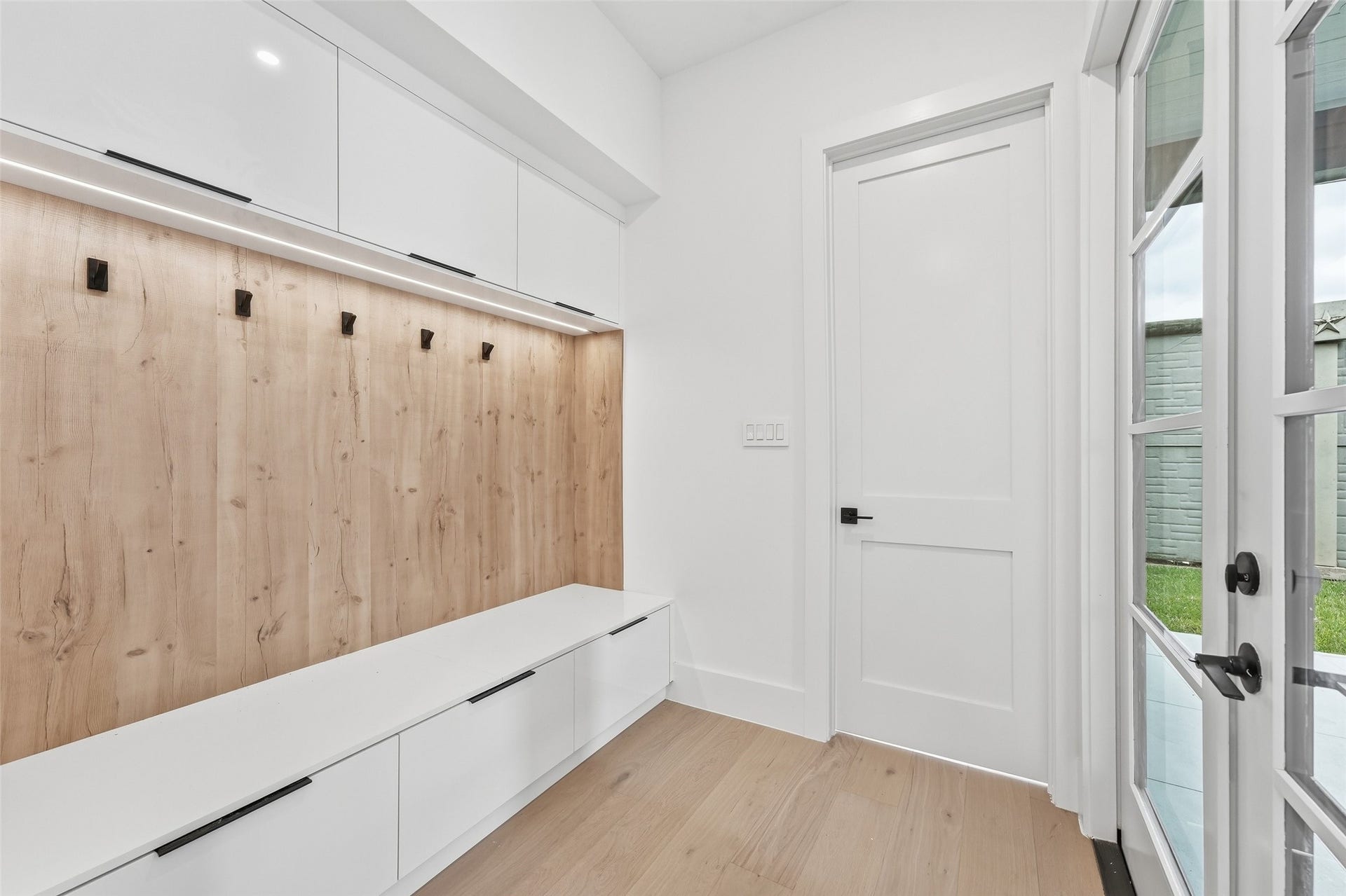 519 W 30th Street, Houston, TX 77018 A thoughtfully designed mudroom with a built-in bench, concealed storage, overhead cabinetry, and convenient hooks creates an organized drop zone just inside the home.