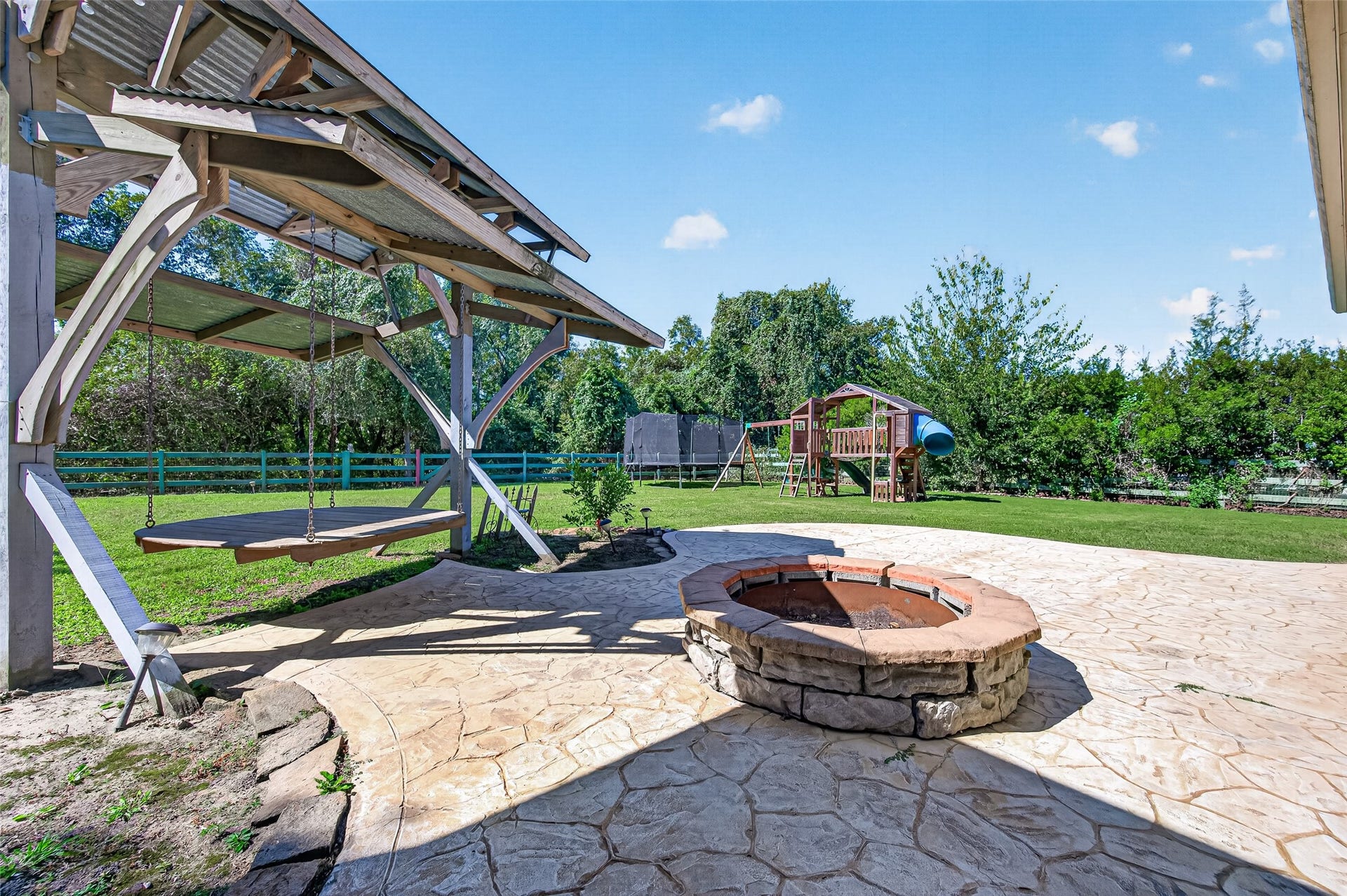 5119 Water Oak Crescent, Fulshear, TX 77441 backyard oasis! Massive covered patio with stone pillars, stamped concrete extension, built-in fire pit, and plenty of green space to entertain.