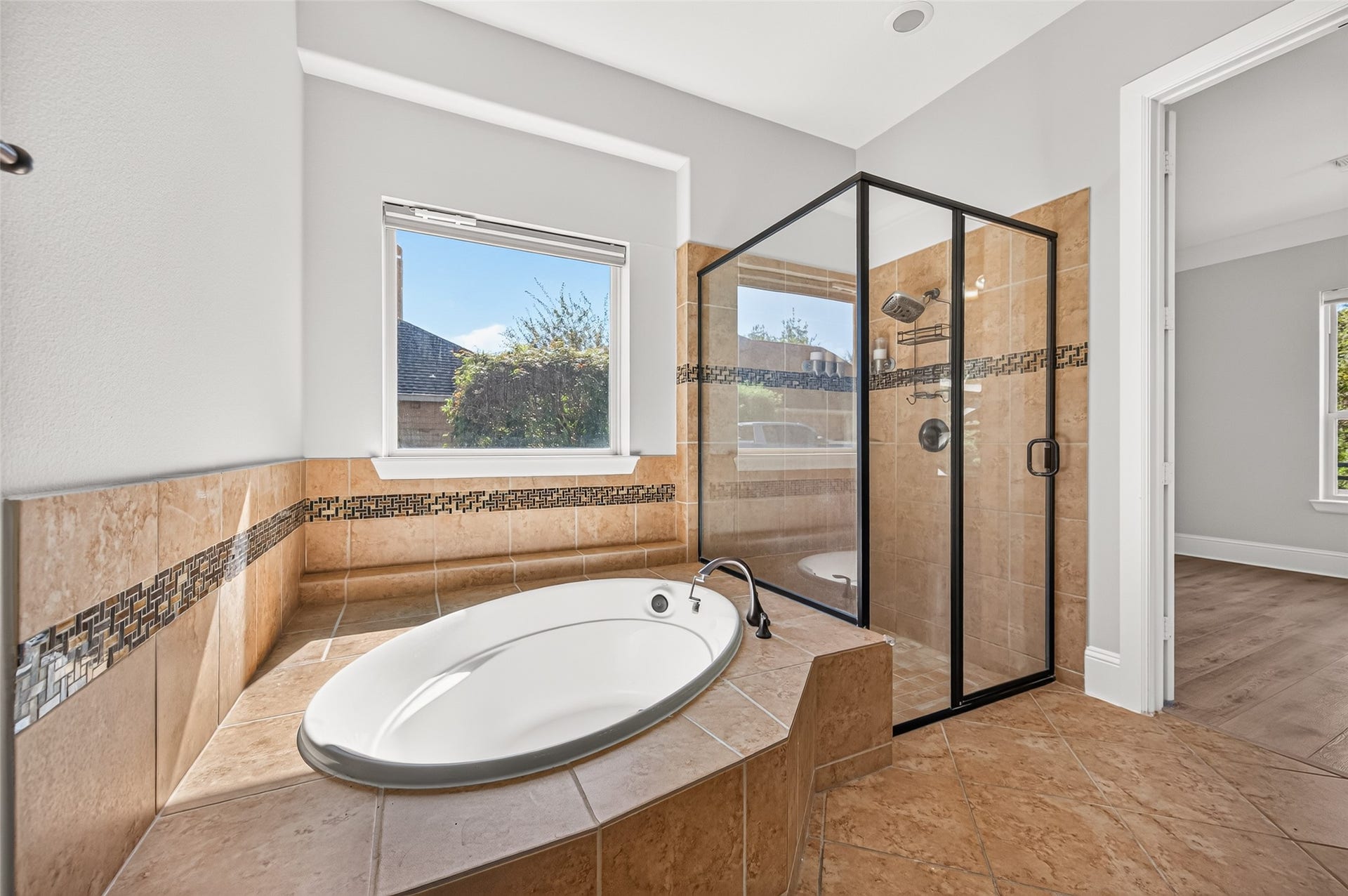 5119 Water Oak Crescent, Fulshear, TX 77441 Spa-like primary bath! Indulge in the deep corner soaking tub with elegant tile detailing. Features a massive granite-topped vanity with dual sinks, rich wood cabinetry, a large framed mirror, stylish lighting, and a massive walk-in layout.