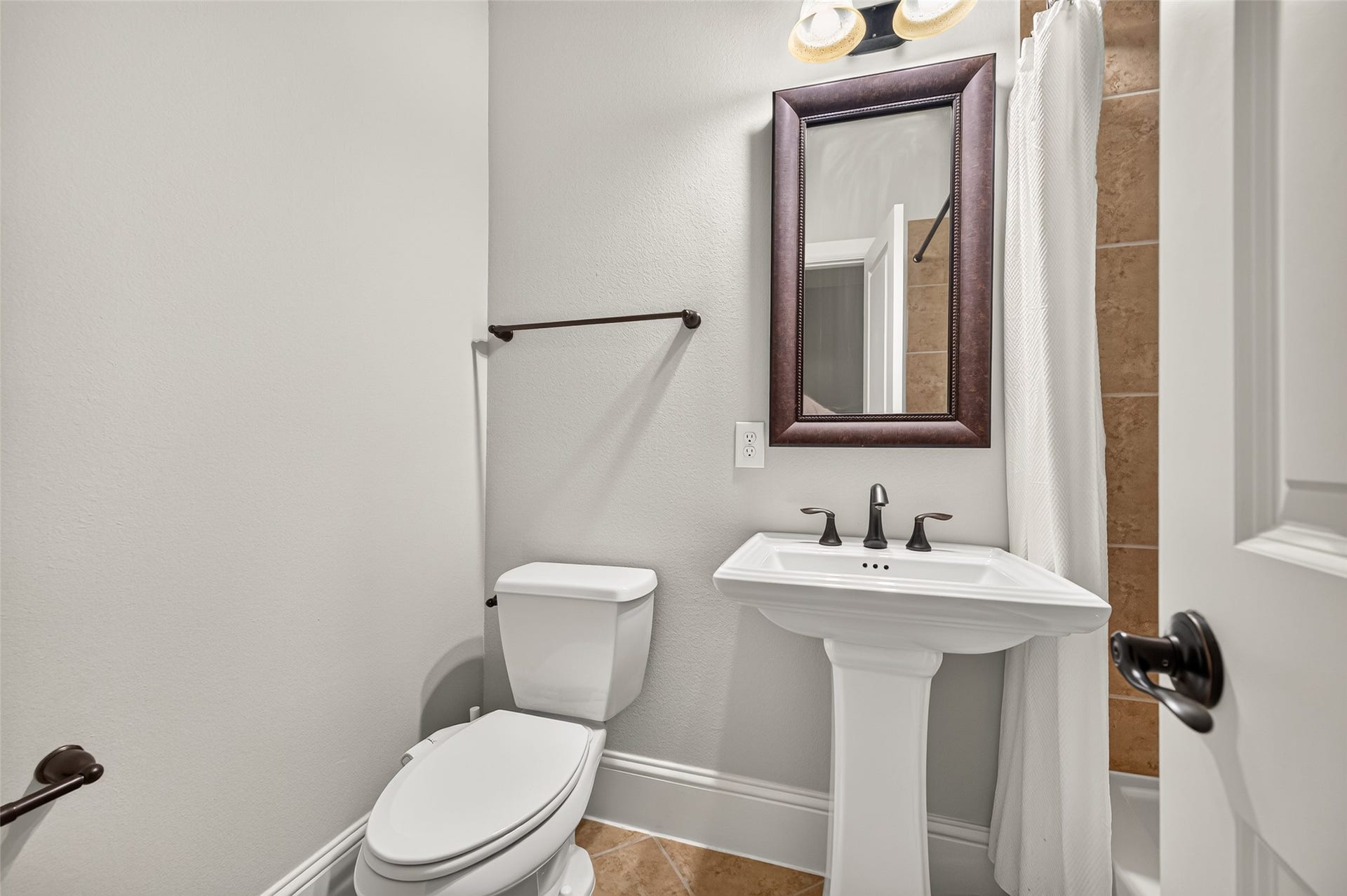 5119 Water Oak Crescent, Fulshear, TX 77441 Conveniently located powder room perfect for guests! Features a classic porcelain pedestal sink, elegant oil-rubbed bronze fixtures, a framed mirror, and durable tile flooring.