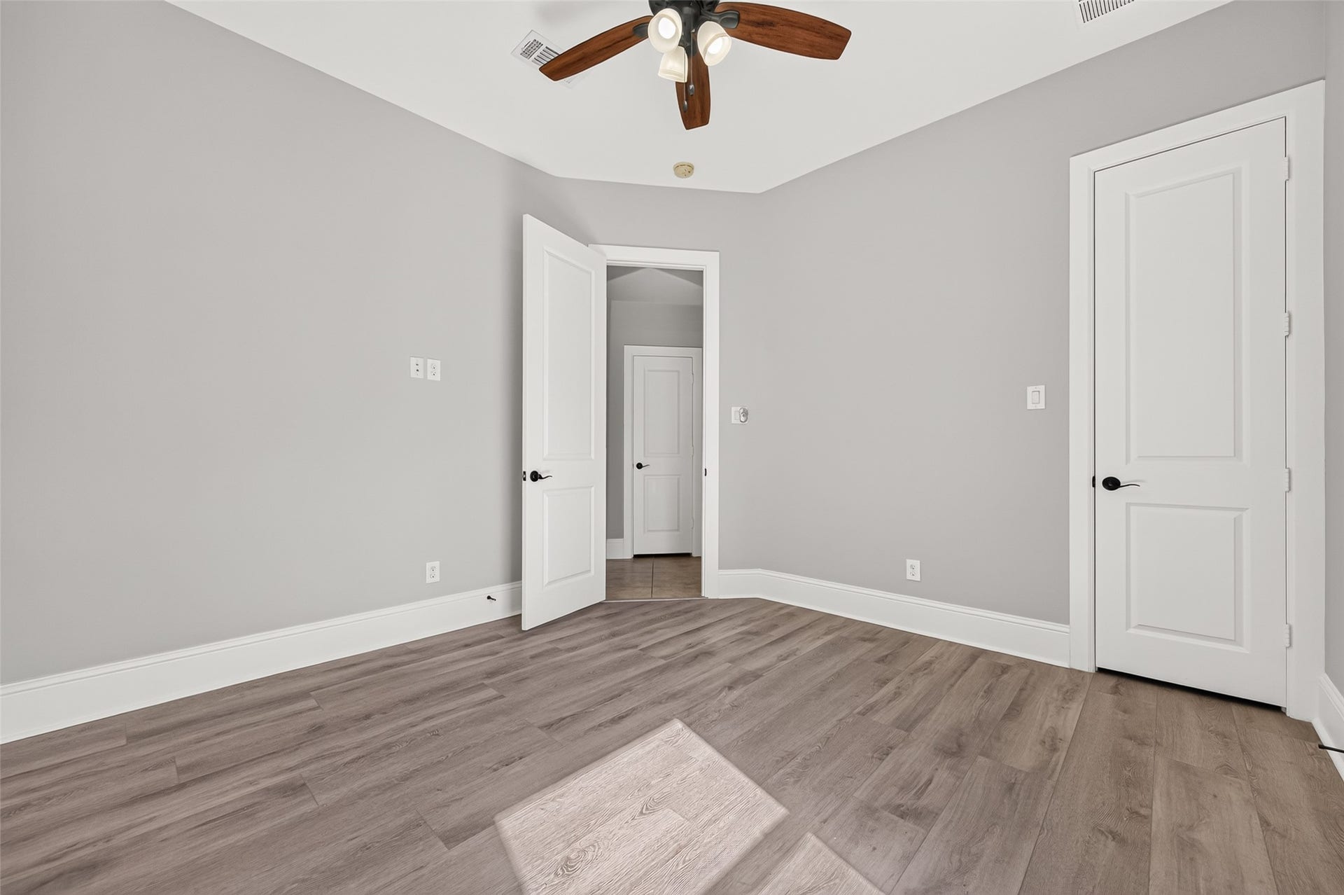 5119 Water Oak Crescent, Fulshear, TX 77441 Versatile downstairs guest bedroom! Showcases a stunning rustic wood-plank accent wall, modern wood-look flooring, a stylish ceiling fan, and an arched window providing natural light and serene front-yard views.