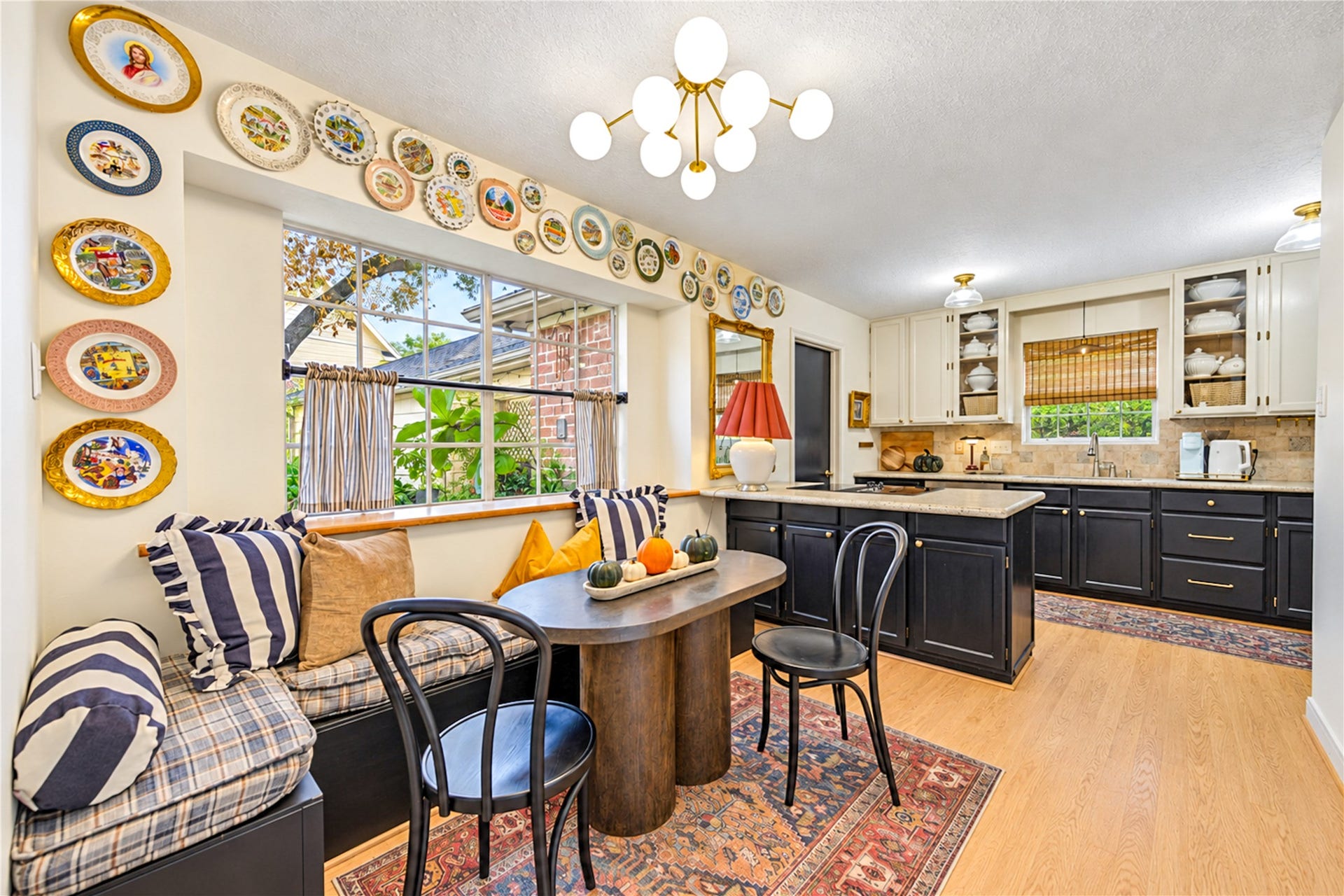 11423 Inwood Drive, Houston, TX 77077 A charming breakfast nook that makes everyday dining feel special! The cozy built-in window seat overlooks lush greenery, creating the perfect spot for morning coffee or leisurely weekend breakfasts. A stylish statement chandelier and beautiful wood floors add warmth, while the seamless connection to the kitchen makes everything from casual meals to entertaining feel effortless. Designer personality shines in every detail!