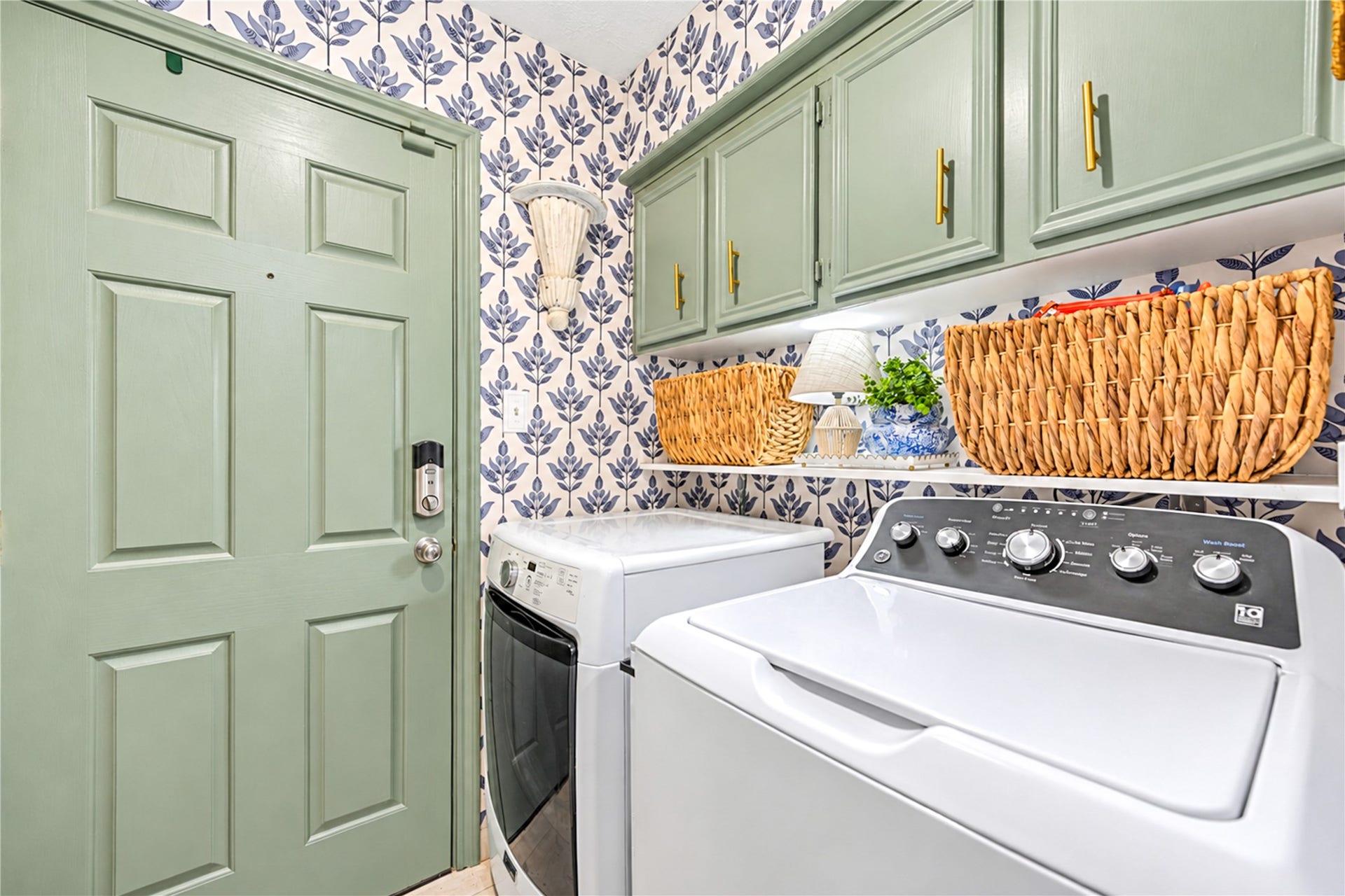 11423 Inwood Drive, Houston, TX 77077 Who says laundry day can't be stylish? This cheerful first-floor laundry room brings personality to everyday chores with playful botanical wallpaper, soft sage-green cabinetry and a colorful patterned backsplash. Thoughtfully designed with generous countertop space for folding and upper cabinets for storage, this charming space proves that even the most practical rooms can be filled with designer flair!