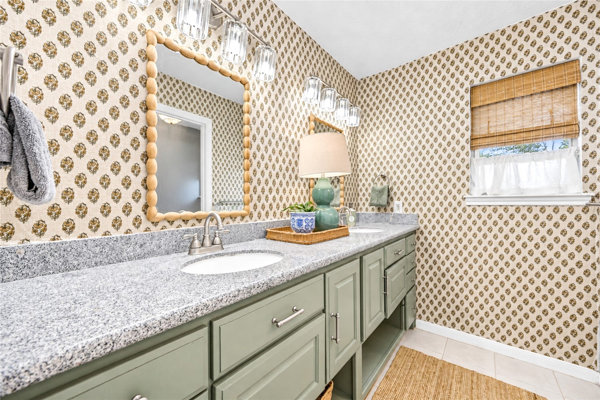 11423 Inwood Drive, Houston, TX 77077 Designer charm continues into the second upstairs bathroom! A spacious vanity with soft sage-green cabinetry, decorative tile backsplash and a beautifully framed mirror creates a fresh, inviting atmosphere. Natural light filters through the window, while thoughtful finishes add warmth and personality. A stylish and functional space that makes everyday routines feel a little more special!