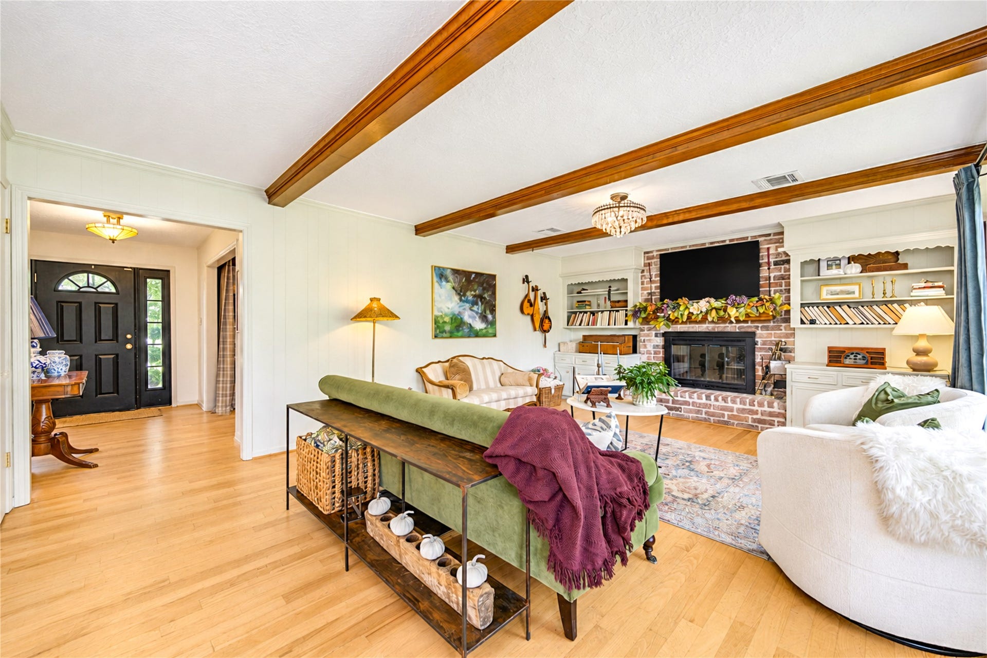11423 Inwood Drive, Houston, TX 77077 A fresh perspective on comfortable living! From this inviting angle, the living room showcases its soaring ceilings, exposed wood beams and beautiful wood floors. Thoughtfully curated designer touches bring warmth and personality, while the open connection to the kitchen keeps everyone part of the conversation. Whether hosting friends or enjoying a relaxing evening at home, this space makes everyday moments feel special!