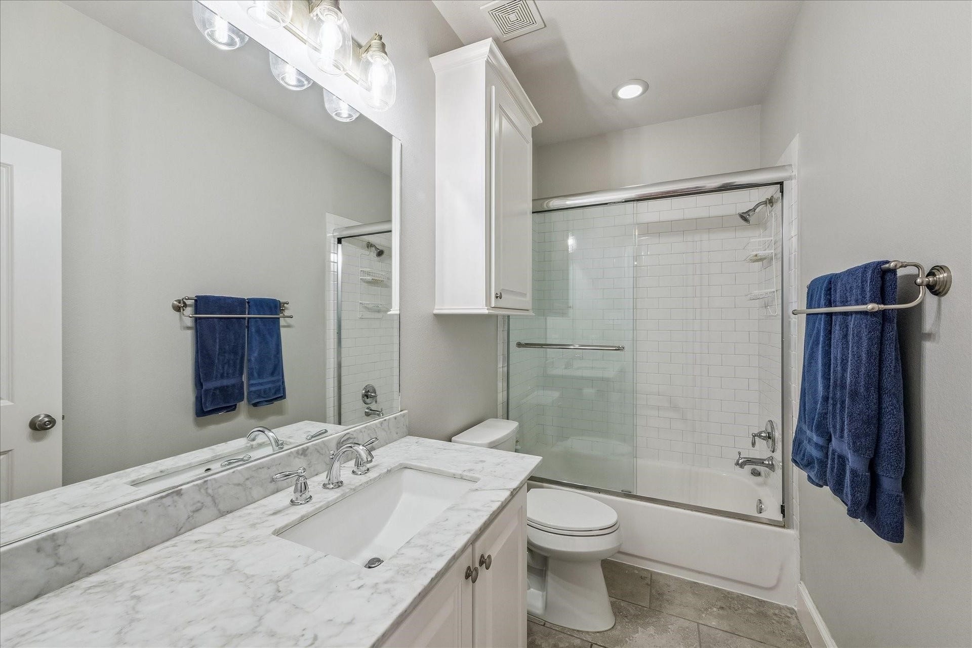 209 Queen Road, Clear Lake Shores, TX 77565 Upstairs full bathroom with modern fixtures, a glass-enclosed shower-tub combo, ample storage and a bright, clean aesthetic