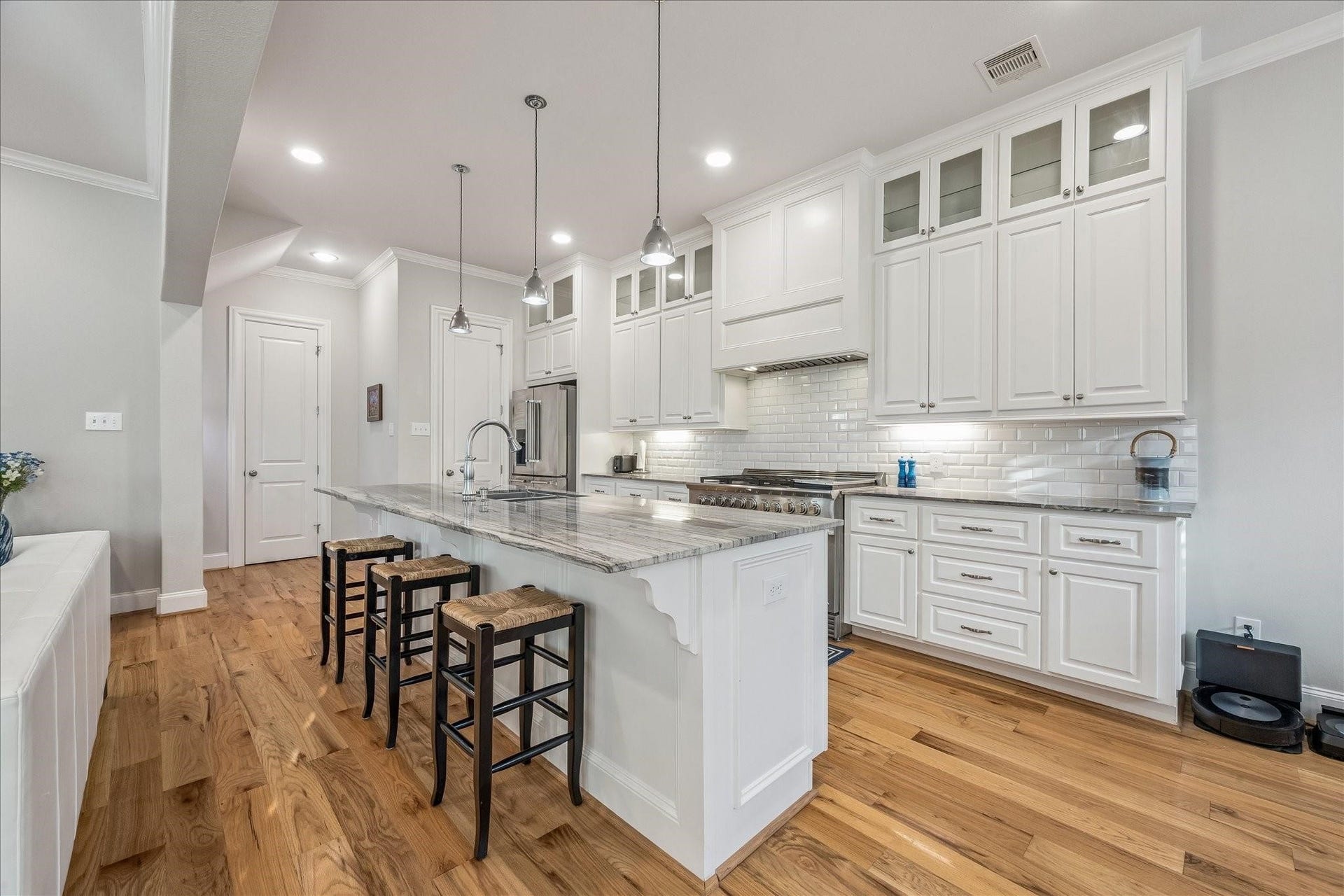 209 Queen Road, Clear Lake Shores, TX 77565 This modern kitchen features custom cabinetry, beautiful quartz countertops, and a large island with seating to gather around. The pendant lighting, subway tile backsplash and glass accents add a clean, stylish touch.