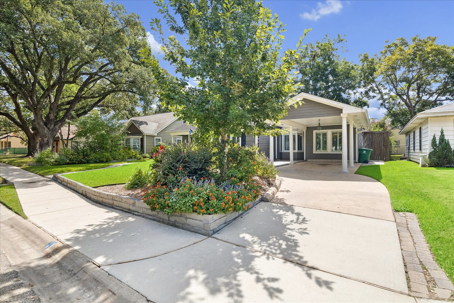 1611 Gardenia Drive, Houston, TX 77018 Lush landscaping wraps the front lawn and continues alongside the driveway, adding color and character beneath mature shade trees. An extended covered parking area offers convenient everyday access while complementing the homes classic Oak Forest setting.