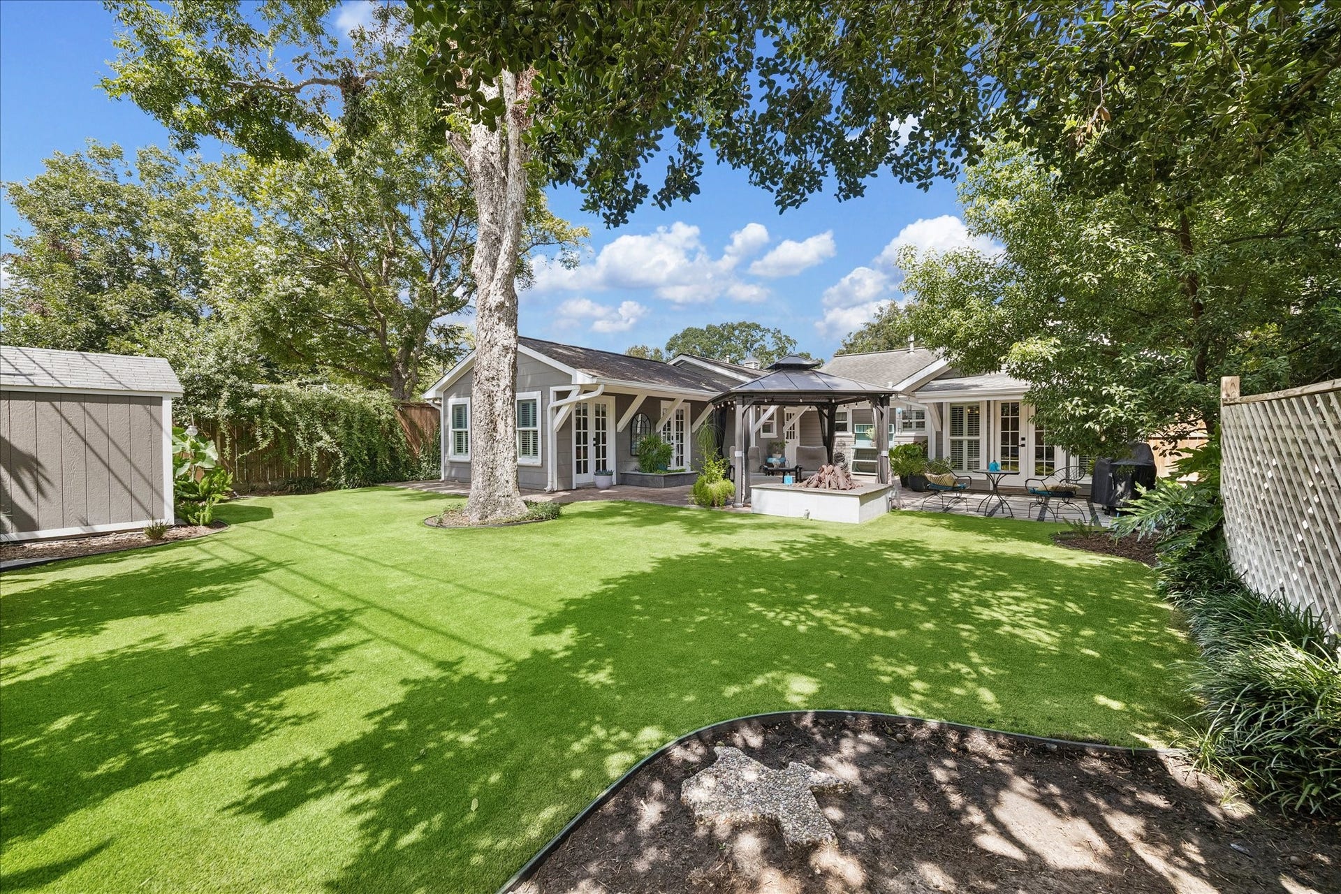 1611 Gardenia Drive, Houston, TX 77018 Mature trees frame the expansive backyard, offering a generous stretch of turfed green space while the patio and gazebo remain tucked closer to the home.