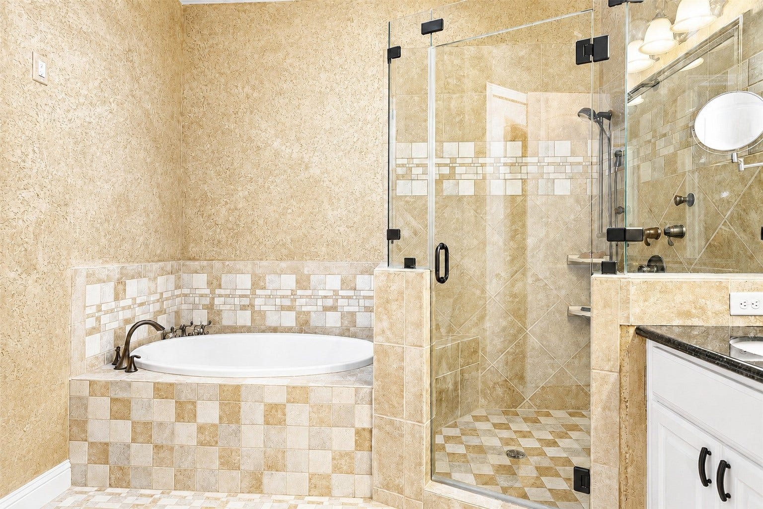 Spa-inspired ensuite bath showcasing a tiled soaking tub and frameless glass shower with intricate tilework and refined finishes.