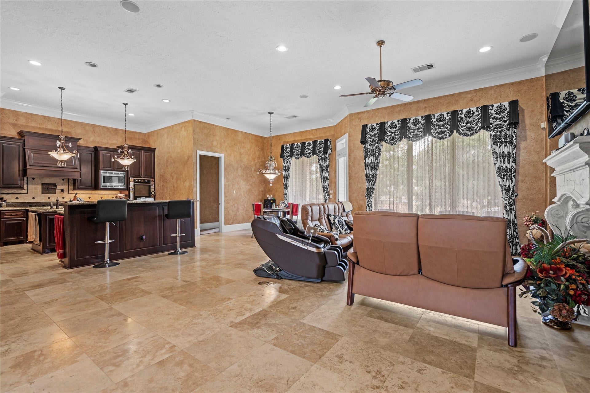 Expansive open-concept living area seamlessly connects to the updated kitchen, enhanced by soaring ceilings, abundant natural light, and polished stone flooring.