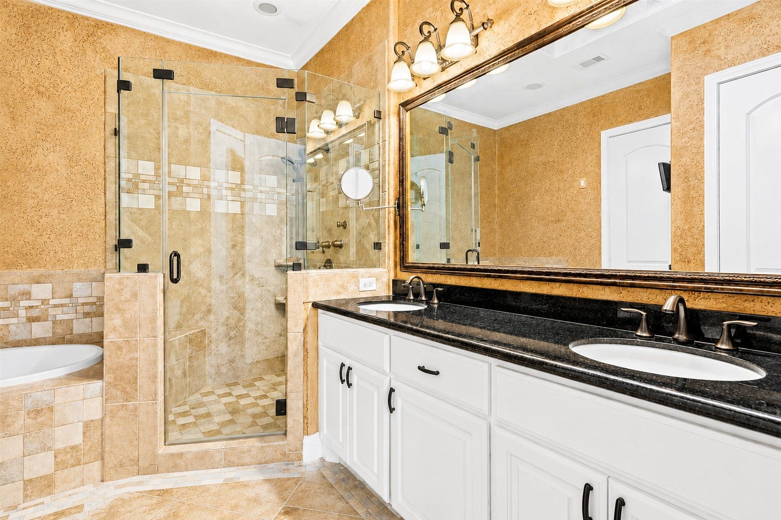 Ensuite bath featuring a dual-sink granite vanity, frameless glass shower, tiled soaking tub, and refined designer finishes.