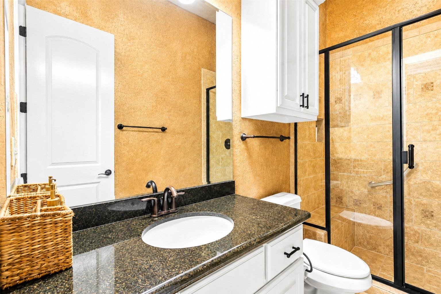 Well-appointed bathroom featuring a granite vanity, ample cabinetry, and a tiled walk-in shower with glass enclosure.