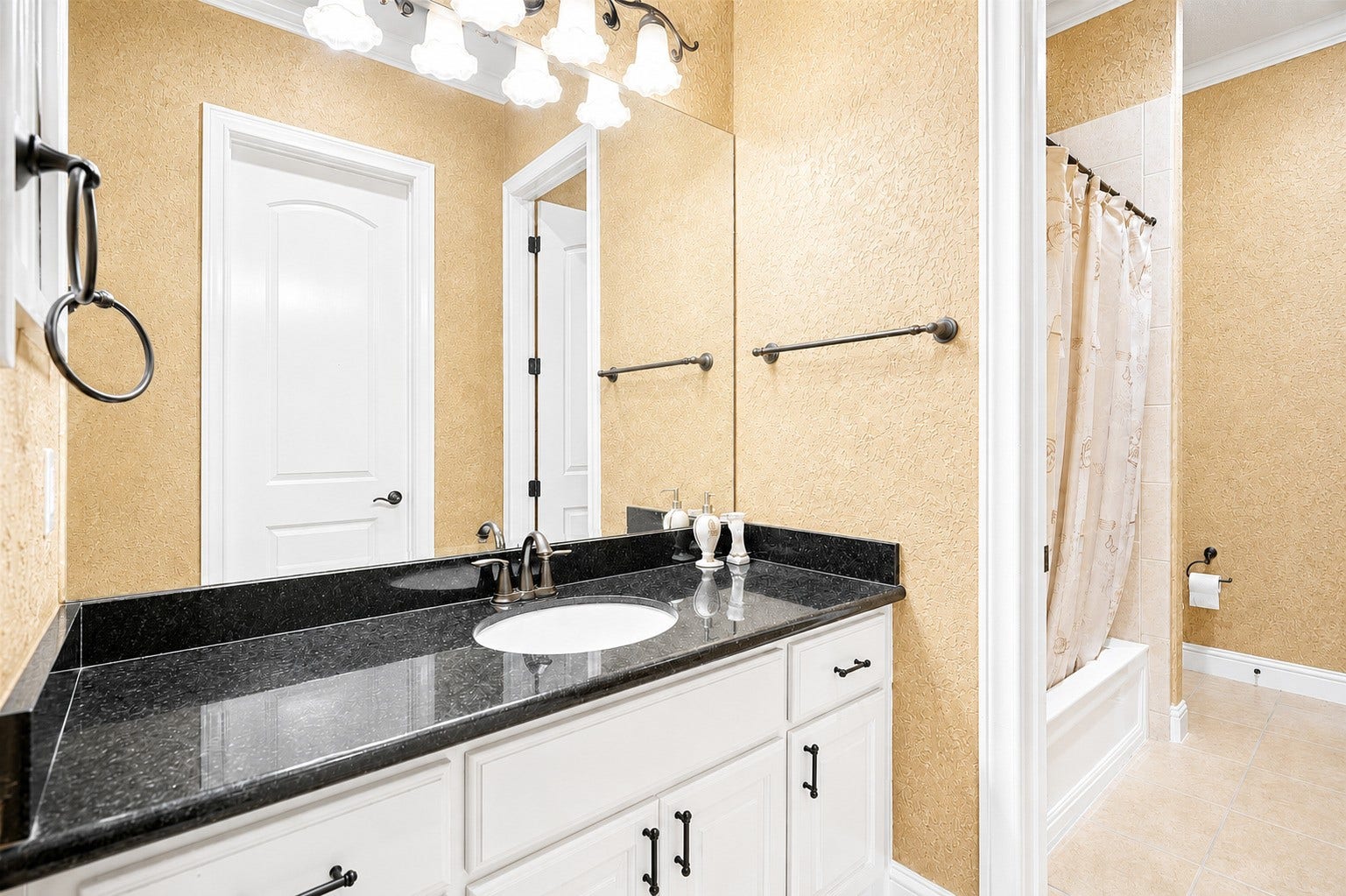 Bathroom featuring a granite vanity, large wall mirror, and a separate tub and shower area.