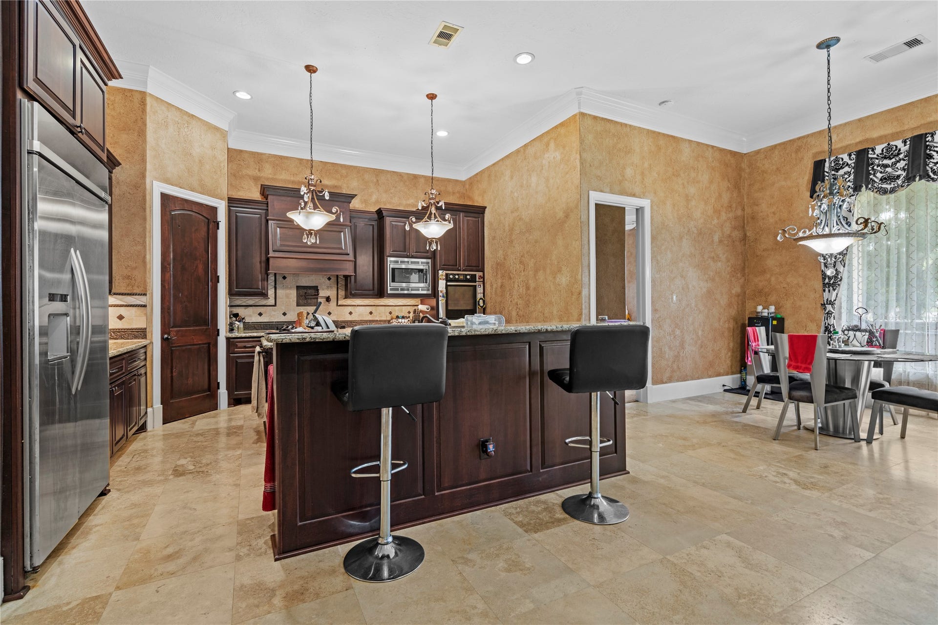This kitchen showcasing rich wood cabinetry, a generous granite island, stainless steel appliances, and an adjoining breakfast area filled with natural light.