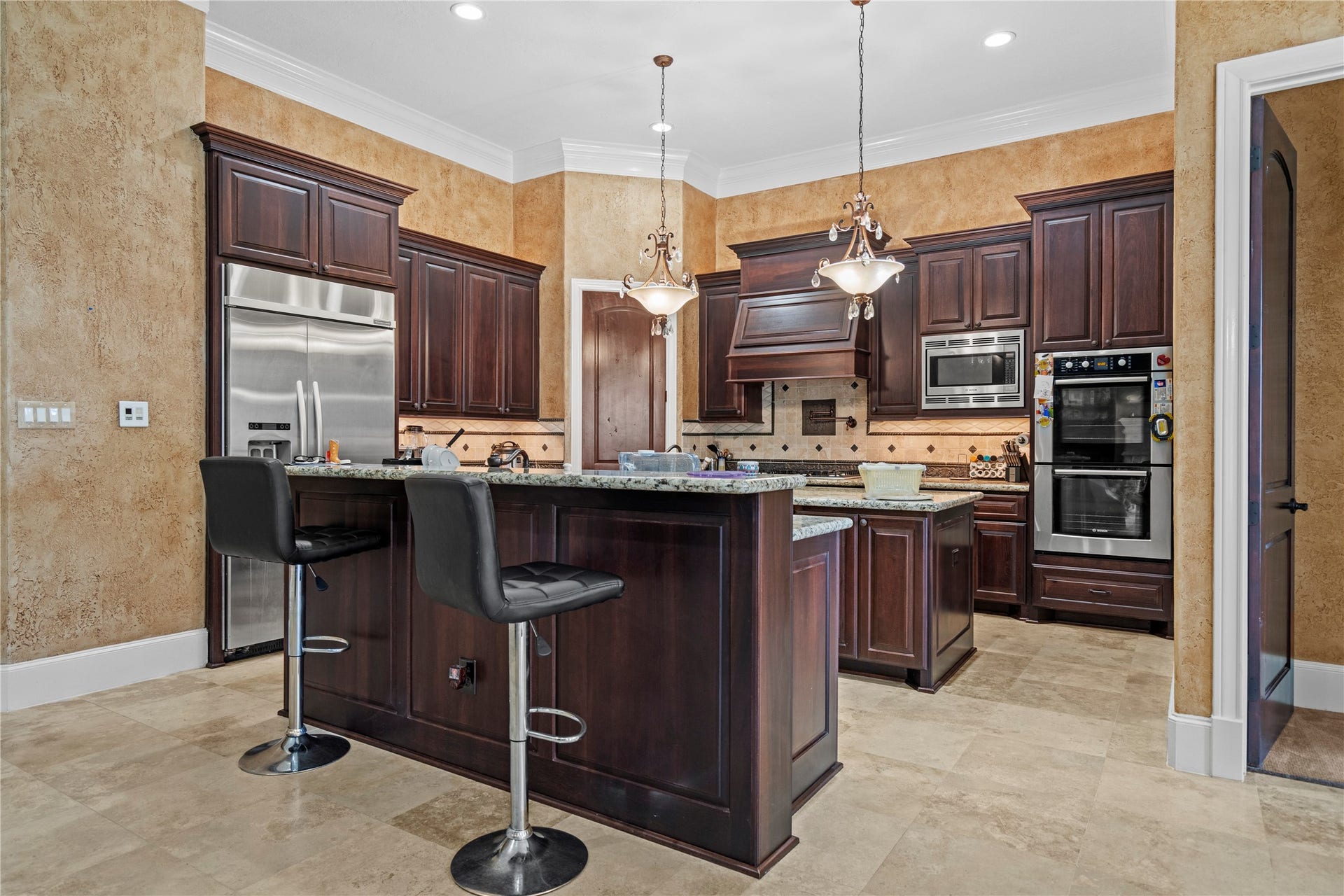 This kitchen showcases finely crafted cabinetry, granite counter tops with more space for storage and designer pendant lighting.