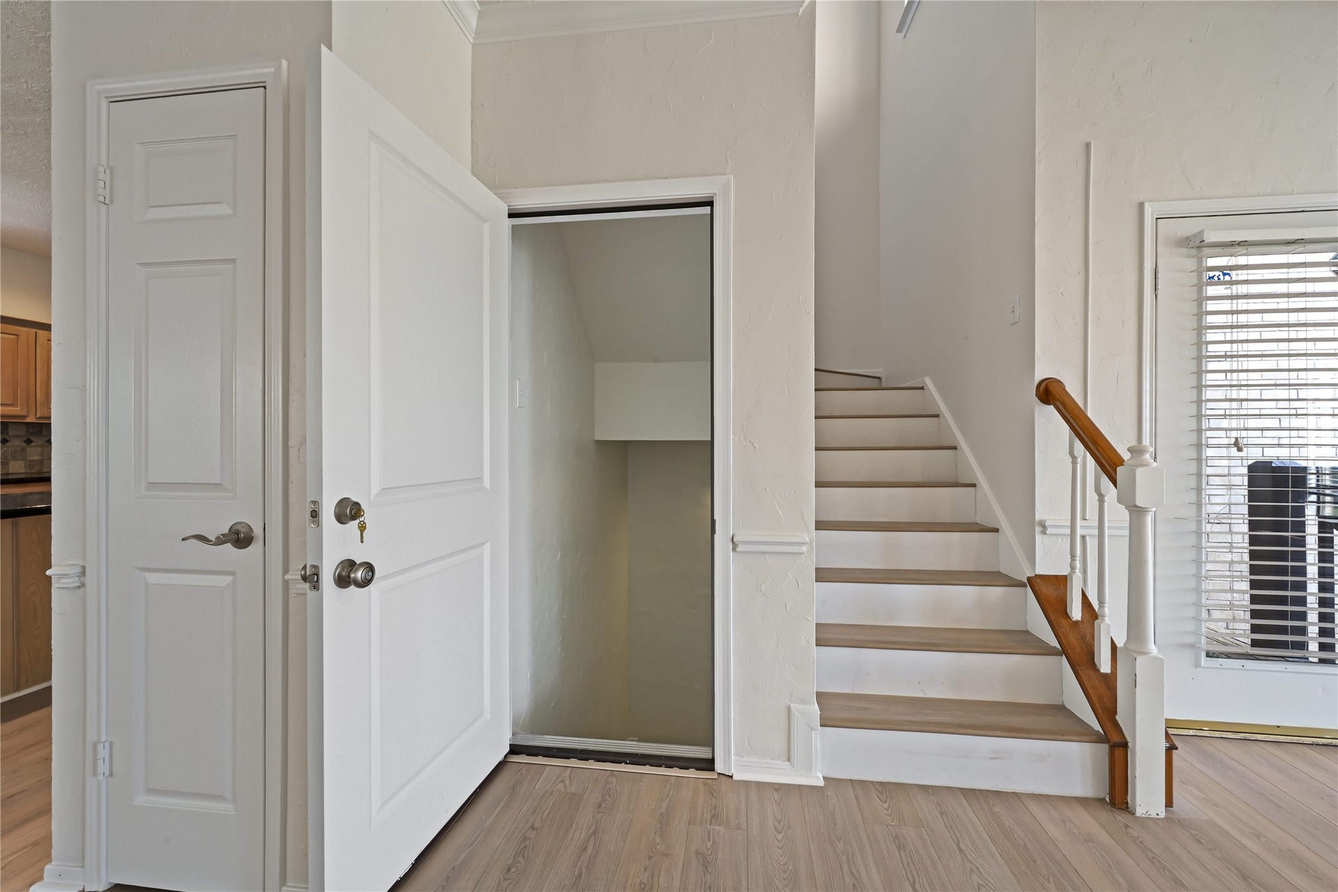 2607 Sailboat Drive, Houston, TX 77058 A well-lit entryway features a staircase with elegant wooden handrails, a convenient storage closet, and a view into a bright kitchen area, enhancing the home's welcoming appeal.