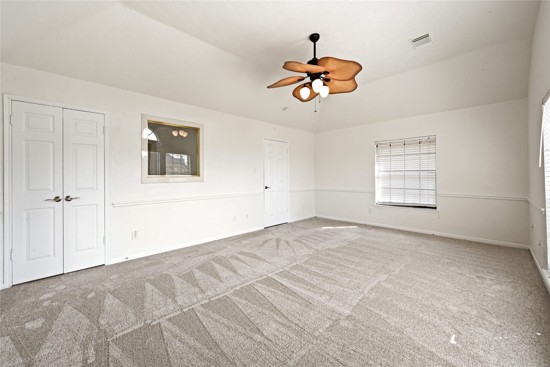 2607 Sailboat Drive, Houston, TX 77058 Spacious bedroom with fresh carpeting, a unique ceiling fan, and abundant natural light from multiple windows.