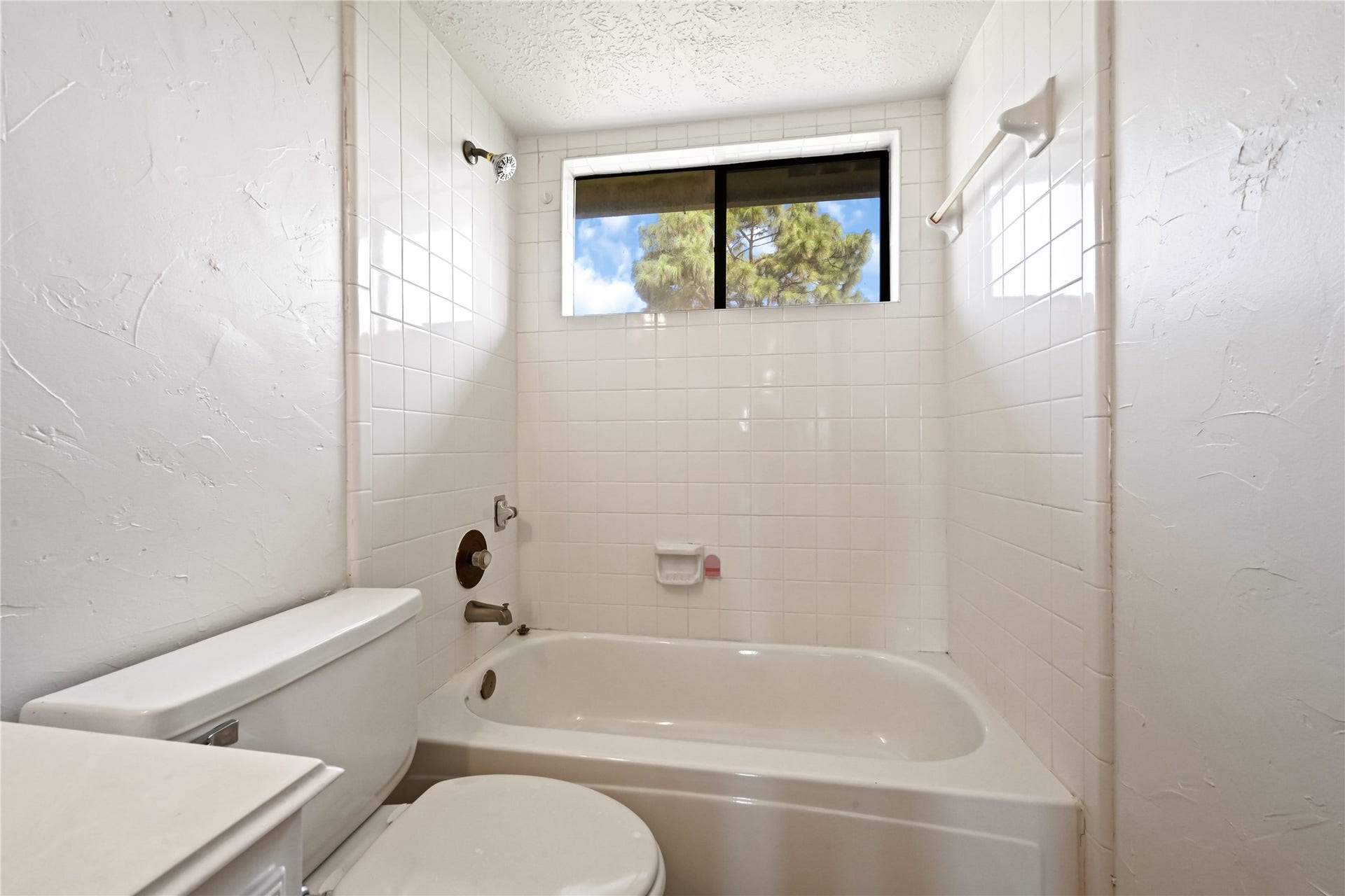 2607 Sailboat Drive, Houston, TX 77058 Bright bathroom featuring a classic white tile bathtub with a window above, providing natural light and a serene view.
